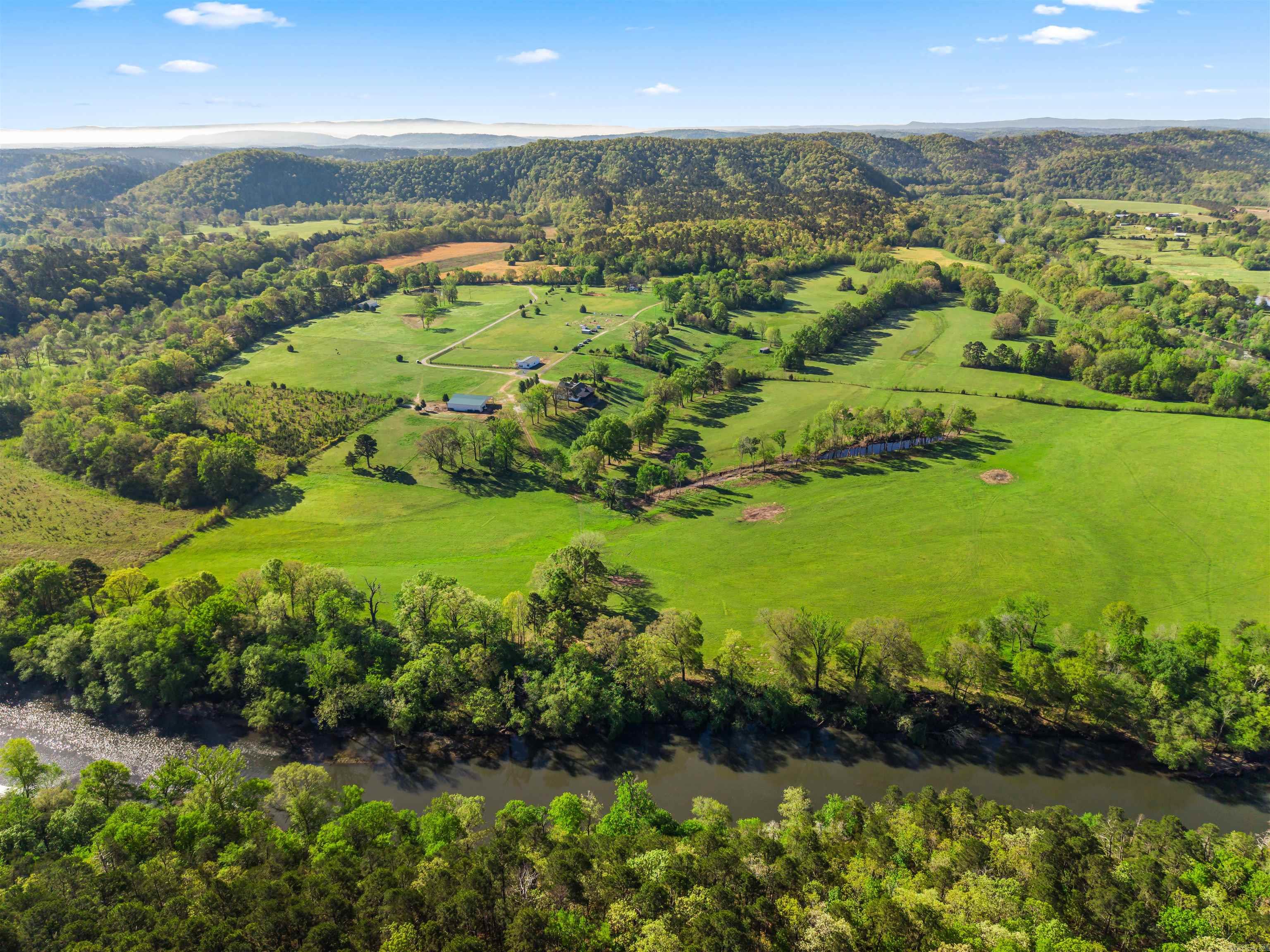 Where the Ouachita River meets refined country living. 81.87+/- acres of stunning riverfront land in Mount Ida, AR — gated entry, cross-buck wood fencing, rolling pastures, and mountain views.  COMPLETELY REMODELED MAIN RESIDENCE (4,340 sq ft | 6 bed | 3.5 bath) features a vaulted great room with floor-to-ceiling stone fireplace, chef's kitchen, formal dining, sunroom, primary suite with French doors to the wraparound deck, and a stacked-stone outdoor fireplace. A finished walk-out basement apartment (2 bed | 1 bath) with its own full kitchen offers incredible flexibility.  THE LUXURY BARNDOMINIUM (1,800 sq ft | 2 bed | 2 bath) has a full granite kitchen, shiplap fireplace, and spa rainfall shower — built-in rental income on the river.  A 2,800 SQ FT UNFINISHED BARNDOMINIUM shell is framed, insulated, and wired for your vision.  The 2024-BUILT EQUESTRIAN BARN (5,184 sq ft) includes 4 stalls, tack room, wash bay, hay storage, and covered riding area. Four self-contained living spaces. One irreplaceable riverfront estate.  Live the life. Own the river.
