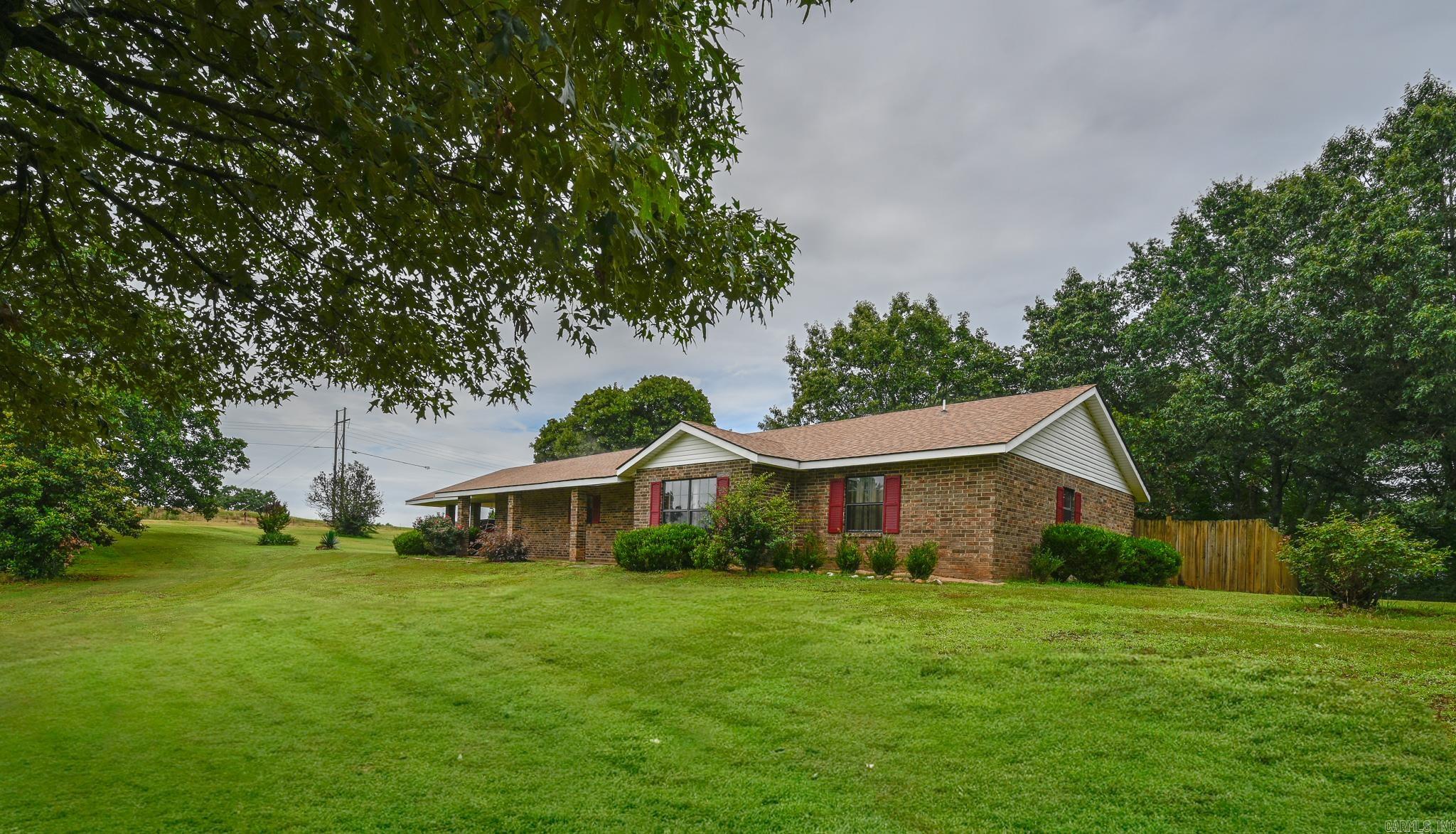 Beautiful brick home situated on approximately 3.1 acres in a peaceful country setting! Offering 3 bedrooms, 2 bathrooms, and 1,875 sq. ft., this property combines comfortable living with the space and privacy you've been looking for. Inside, you'll find a spacious living room centered around a wood-burning brick fireplace, a formal dining room, and a large kitchen with abundant cabinetry and workspace. The primary suite features a walk-in shower and soaking tub, creating a comfortable retreat. Recent improvements include a newer roof and newer HVAC system, providing added value and peace of mind. Outside, enjoy the beauty of the acreage from the covered front and rear porches. Additional amenities include a private well, fenced backyard, two-car carport, and an oversized workshop/garage perfect for storage, hobbies, equipment, or projects. The gently rolling acreage, mature trees, and scenic surroundings make this property a rare find with plenty of room to enjoy the outdoors.