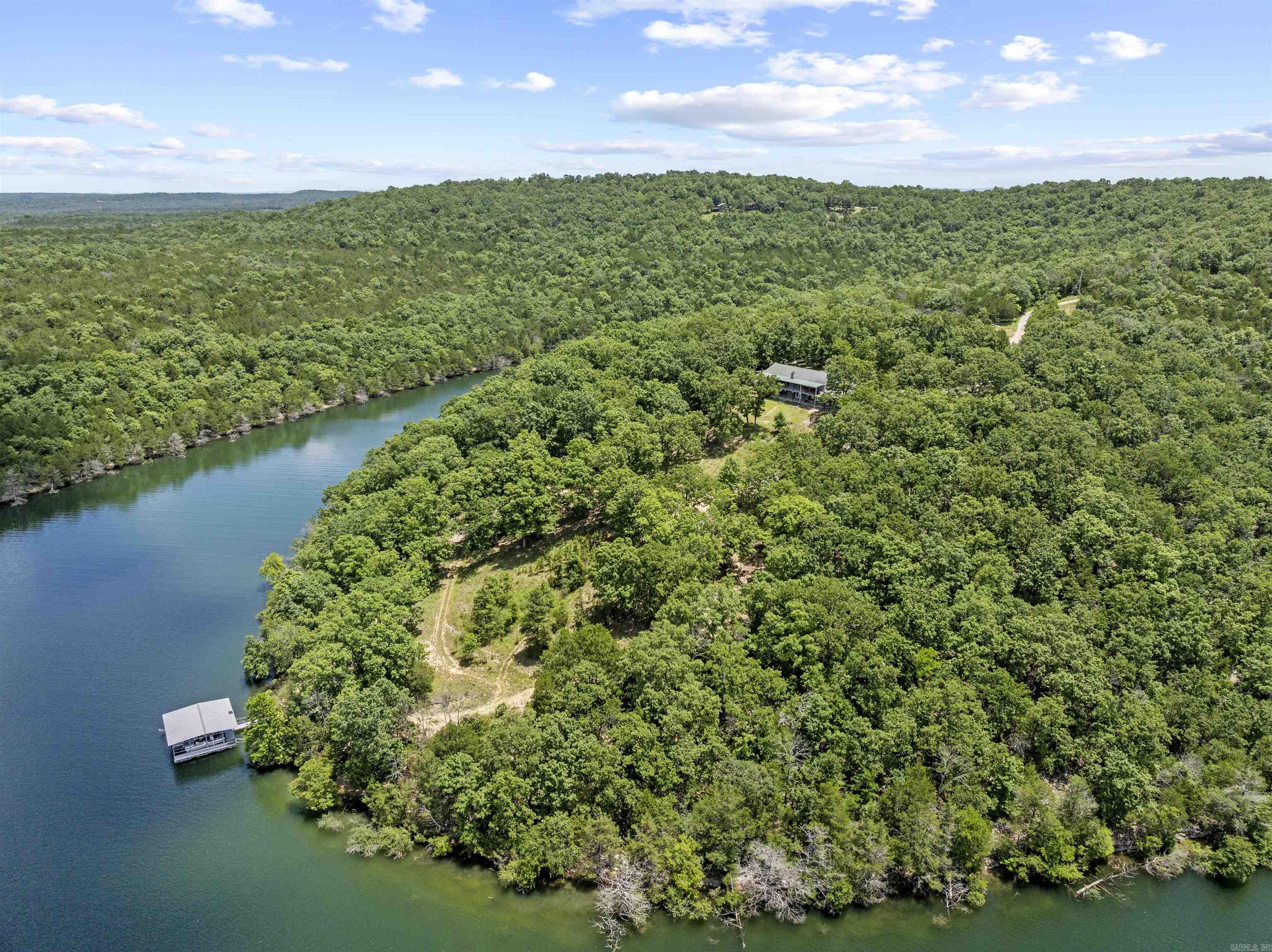 A rare opportunity—62± acres on a private peninsula, surrounded by Bull Shoals Lake on three sides. Unmatched privacy, panoramic views, & direct lake access set the stage for lake life at its best. The fully furnished 3-bed, 3-bath home is made for relaxing & entertaining, with a wraparound deck. The walk-out basement offers a second living area, bonus room, storm shelter, kitchenette, & hot tub. Your private two-stall dock with lifts conveys—a rare find on Bull Shoals, where no new dock permits are issued. Both boats can convey with an acceptable offer—lake days start instantly. The land offers a mix of woods, clearings, trails, wildlife, & multiple build sites—perfect for a family retreat, vacation compound, or future development. Extras: detached 2.5-car garage with studio apartment, carport for boat storage, & an outdoor shower. Just 10 minutes from Lead Hill & 5 minutes from the nearest boat ramp at the end of Camp Galilee Rd (MC 2061). Secluded yet accessible—a legacy property like no other.