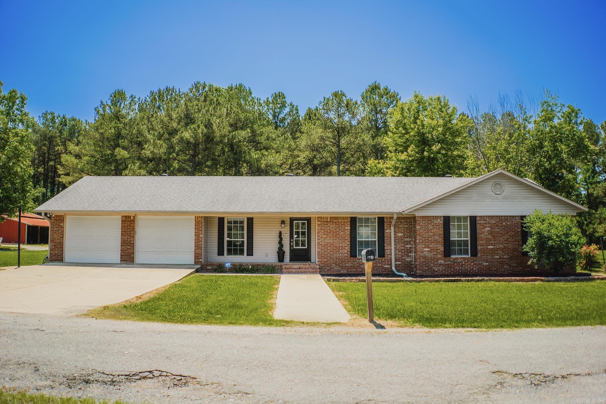If you’ve been looking for a little space outside of town without giving up convenience, this one-story brick home offers the best of both worlds. Located at the end of a quiet street with only four homes, the property sits on approximately 4 acres with a peaceful country setting, open pasture, mature trees, and a large red barn.  The home features 4 bedrooms, 2 bathrooms, solid surface flooring throughout, and a functional layout with comfortable living spaces. The den features vaulted ceilings, and the kitchen has a fresh, updated feel with white cabinetry, white countertops, tiled backsplash, and bar seating open to the living area. The dining space overlooks the backyard and brings in plenty of natural light.  Outside, you’ll find a fenced backyard, plenty of room to spread out, and space for animals, gardening, hobbies, or simply enjoying the quiet setting. Additional features include a spacious laundry room and a 2-car garage with extra storage space.  Properties with acreage and this kind of setting close to town are hard to find - call me today to schedule your private showing.