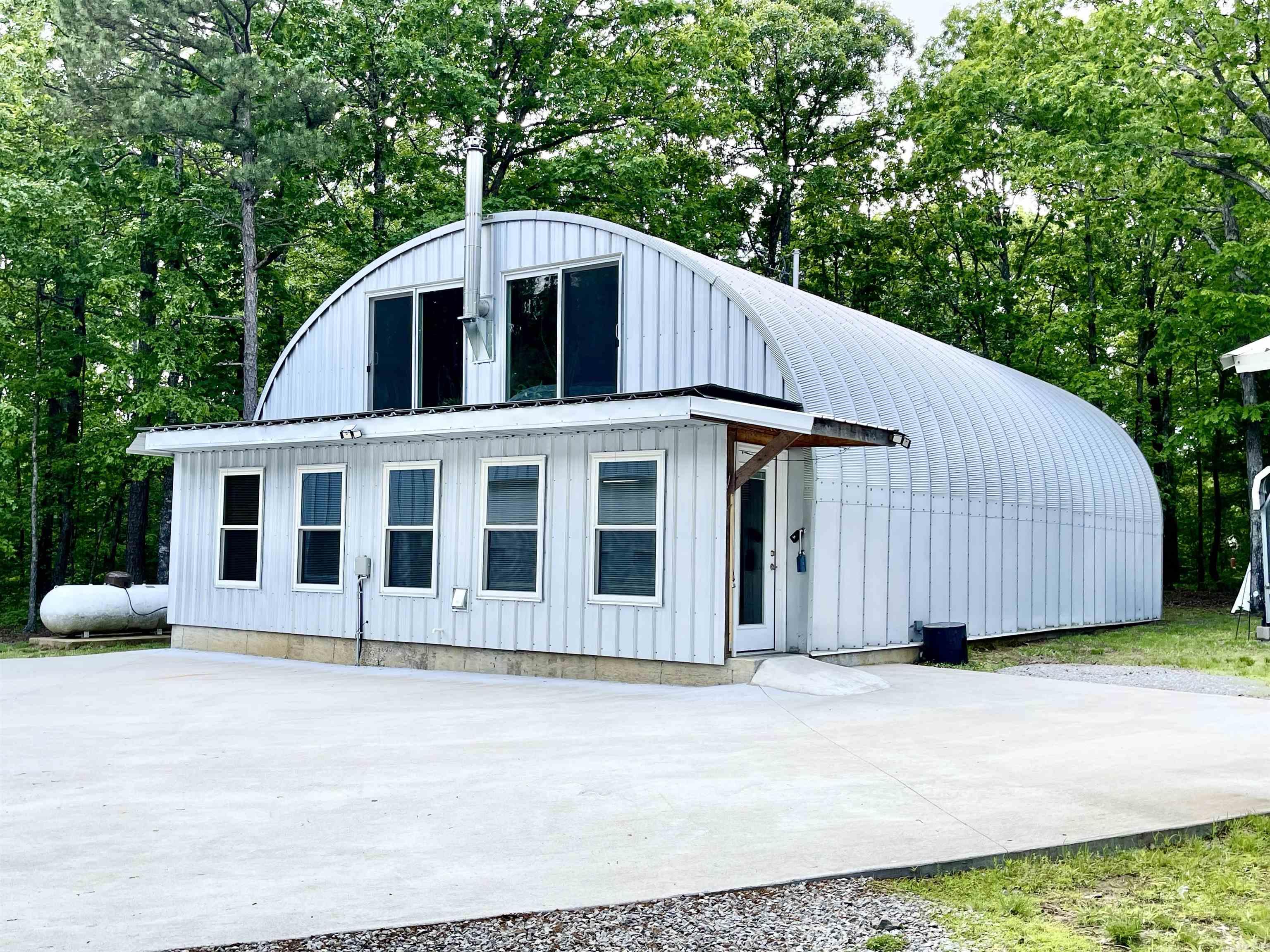 Over 5 acres of privacy and within about 15 minutes of Greers Ferry Lake!  WOW!! Quonset home is 30' X 50' and has 1 1/2 stories with approximately 2200 sq ft of living space! The workshop/boat storage, etc. is even larger - 40' X 58' and also has an upstairs!  House boasts a living room, den/kitchen, 2 BR and 1 bath on main floor and 1 Bedroom and 1 Bath upstairs and space for an exercise room or office! There is a large 2 car carport and 2 large shipping containers for tons of storage! There are 3 mini split units and upstairs has a woodburning stove. Gas water heaters are tankless units and windows are Low-e windows! Shop building is insulated and has water so a bathroom or kitchen could probably be added if needed. Kitchen has beautiful marble countertops. House was built in 2022 and shop building was built in 2024.  You do not want to miss this one!!