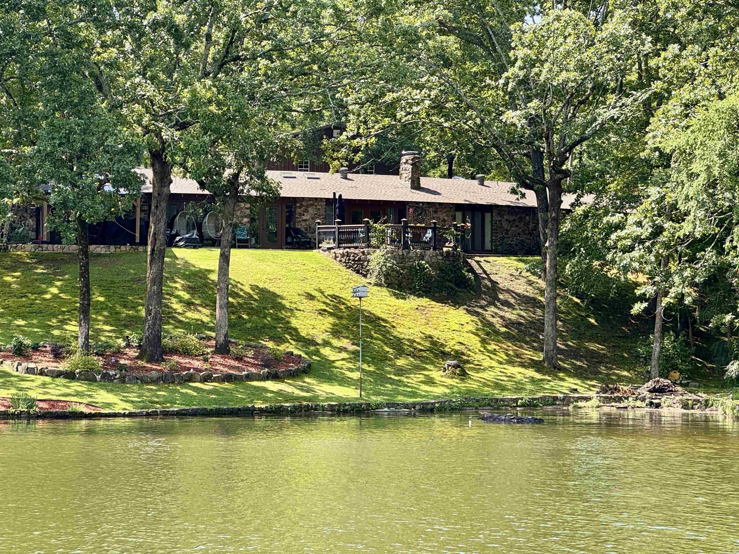 Lakefront Luxury on Lake Hamilton with Guest House, Shop & Boat Dock. Experience exceptional lakefront living on Lake Hamilton in this beautifully furnished 3,287-sq' home featuring 4 bedrooms and 3.5 baths, plus a separate 448-sq' guest house with 1 bedroom and 1 bath. Designed for both comfortable living and entertaining, this single-level home offers stunning lake views, a full bar, abundant skylights, a wood-burning fireplace, and a newly updated kitchen. The primary suite includes a private outdoor shower, creating a relaxing resort-like retreat. Outside, enjoy everything lake life has to offer with a two-stall covered boat dock, 164 feet of seawall frontage, and approximately 0.73 acres of waterfront property. Additional features include a 30' x 36' metal shop, storage shed, and a covered gazebo with an outdoor kitchen—perfect for hosting family and friends. Recent updates include a new roof installed in 2023. Located on a quiet, paved dead-end street surrounded by beautiful homes, this property offers privacy, comfort, and an exceptional waterfront lifestyle.This rare waterfront property combines luxury, recreation, and functionality in one outstanding package