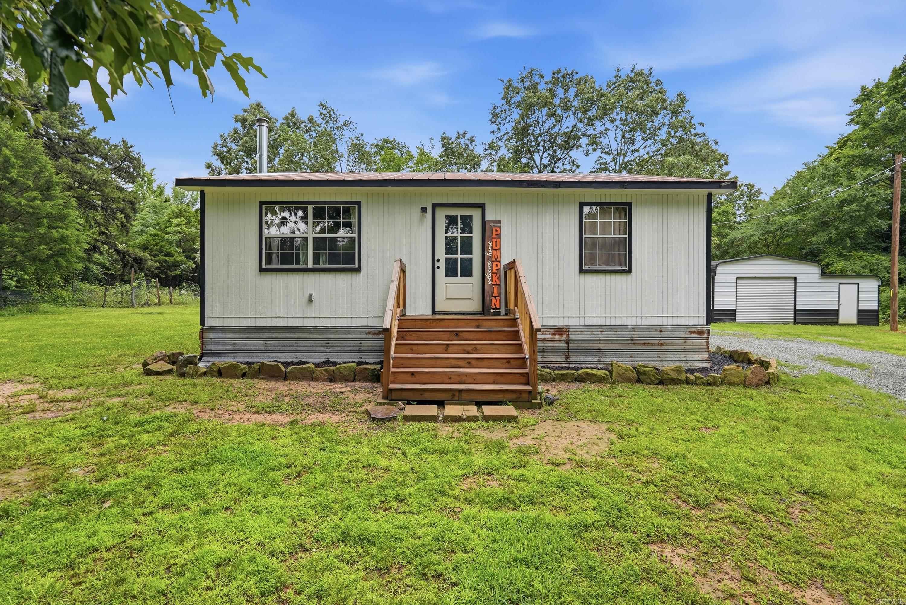 Escape to the peace and privacy of rural Faulkner County with this fully updated cabin-style home on over 7 wooded acres near Guy, Arkansas! Hidden from the road and surrounded by nature, this unique property offers the quiet country lifestyle buyers are searching for while still being just a short drive from shopping, dining, and entertainment.  This 2 bedroom, 1 bathroom home features approximately 1,064 sqft with an open floor plan and a wood burning stove capable of heating the entire home during the winter months. Freshly painted wood siding and a metal roof add to the rustic charm, while extensive recent updates make this property move-in ready. Too many updates to list here — contact us for the full details! Agents, please refer to the attached update document.  Outside you’ll find a large covered back porch overlooking the wooded acreage along with a detached shop building and attached carport. With unrestricted land and endless possibilities for homesteading, recreation, or simply enjoying privacy, this property is truly one of a kind!