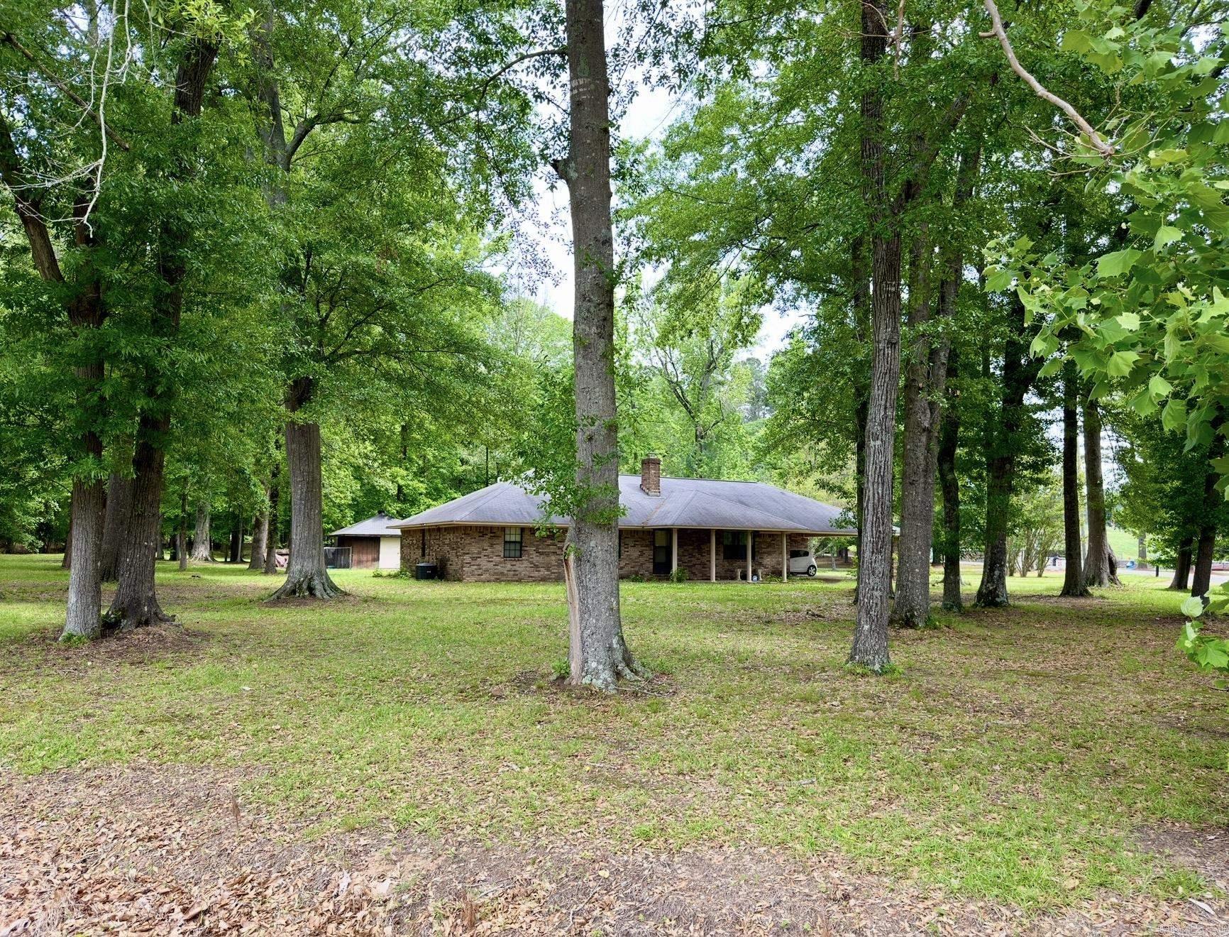 Custom built brick home on 1 acre corner lot close to a variety of recreational activities. Inside you will find a charming brick entry way that adds character with a welcoming vibe. Bricks lead to the grand wood burning fireplace with insert that provides heat, ambiance & nostalgia. The large eat-in kitchen has plenty of cabinet space and is situated next to the formal dining room with sliding glass door. Master bedroom is oversized with full bathroom and walk-in closet. Laundry room/mud room with front & back entry has utility sink. Outside storage building has been converted to dog kennel. Bonus room off carport could be craft room/workshop/storage. Area amenities include dog park, fitness trails, quick access to Henderson State University Campus + more. Prime location for off campus student housing.