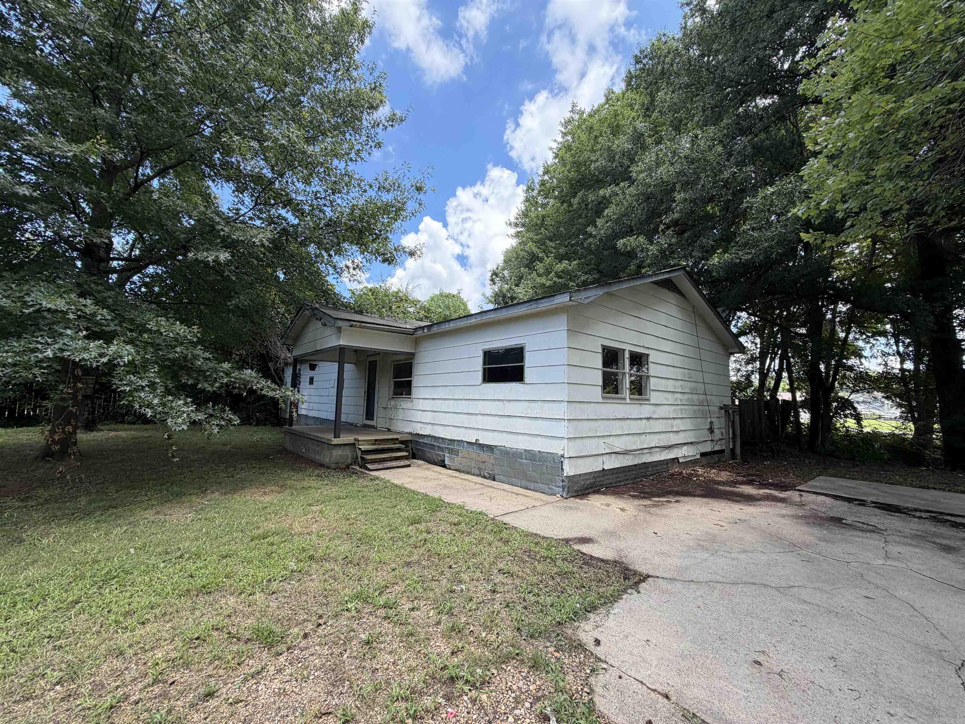 This little country home is in need of some love, it's been rented for 20 plus years and now is vacant being sold "as is" and has approximately 1224 sf. a triangular lot with 0.60 acres of land on the south edge of Paragould. There are two bedrooms with built ins, one with a 1/2 bath and another room where laundry hook ups are located, dining area, kitchen and living room, there is a large parking slab available and covered front porch. Tree lined lot with lots of shade...see agent remarks for entry