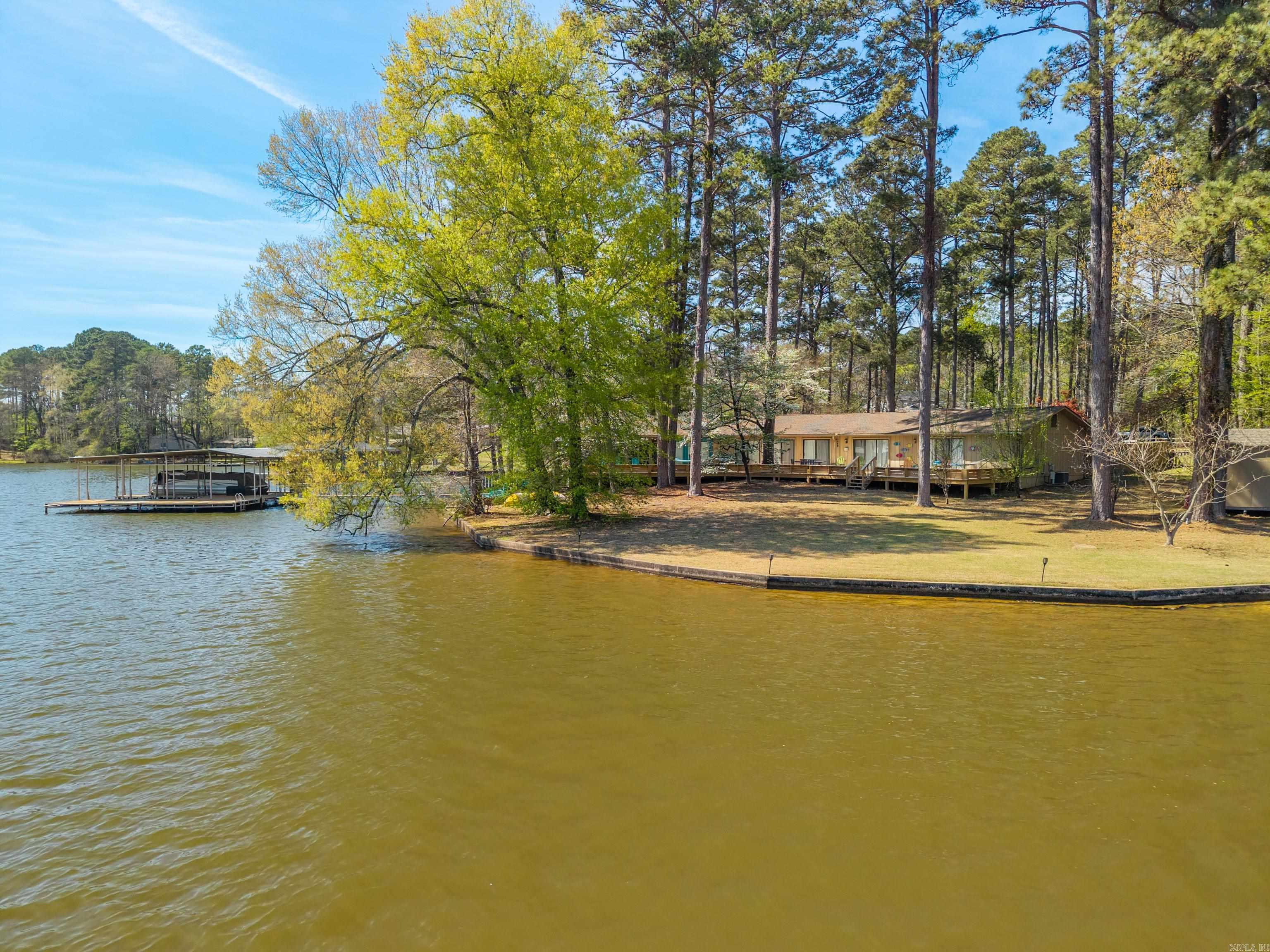 Welcome to your dream lakefront retreat on Lake Hamilton! This beautifully designed 4BR/3.5BA home offers an open-concept living,kitchen, and dining area perfect for entertaining or relaxing. From the moment you enter, you’re greeted with stunning lake views.Vaulted ceilings and a spacious living area create a warm, inviting atmosphere ideal for gatherings or cozy nights in. The bright, cheerfulkitchen features vibrant finishes, ample counter space, and a gas cooktop, making it the heart of the home. Just off the kitchen is aconvenient wet bar—perfect for serving refreshments after a day on the water—along with a large walk-in pantry for added storage andorganization. In addition to four spacious bedrooms, the home includes two versatile bonus rooms currently used as additional sleepingareas—ideal for a home office, gym, or extra guests. With dual primary suites and two separate living areas on opposite sides of thehome, privacy and flexibility are thoughtfully designed throughout. The primary suite features an ensuite bath with a soaking tub,separate walk-in shower, double vanities, and a walk-in closet. Additional highlights include two laundry areas and a whole-homegenerator for