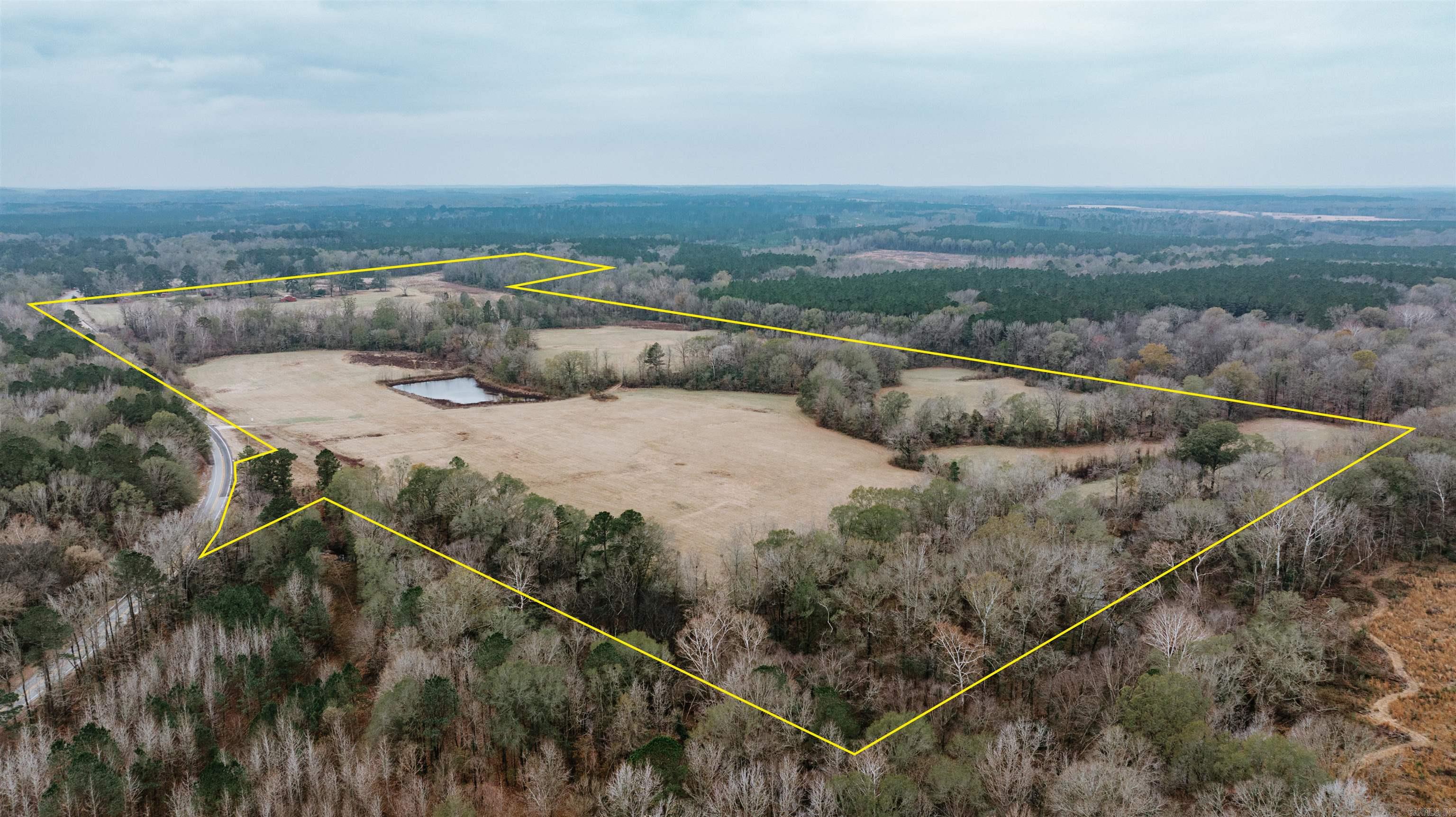 Just 8 miles southwest of Arkadelphia, this 121-acre tract sits in that sweet spot where you’re tucked away enough to feel alone, yet close enough to town that you’re never truly isolated. The land stretches out wide and open, offering room to build a homeplace, run livestock, or simply enjoy a little elbow-room that most folks never get to experience.  Over a hundred acres of clean pasture and hay ground roll across the property, giving you a strong foundation for cattle, horses, or a future hobby farm. There’s an old homesite here too — the kind of spot where you can almost picture smoke coming out of a chimney again, ready for the next family to make memories. With electric and fiber optic already in place, you’ve got the conveniences of today without losing the feel of yesterday.  A year-round creek, pond, and full perimeter fencing add the natural water and structure every working farm needs. And with over half a mile of highway frontage, access is easy no matter what you’re hauling. It's a quiet country with the right kind of connection — private when you want it, close when you need it.