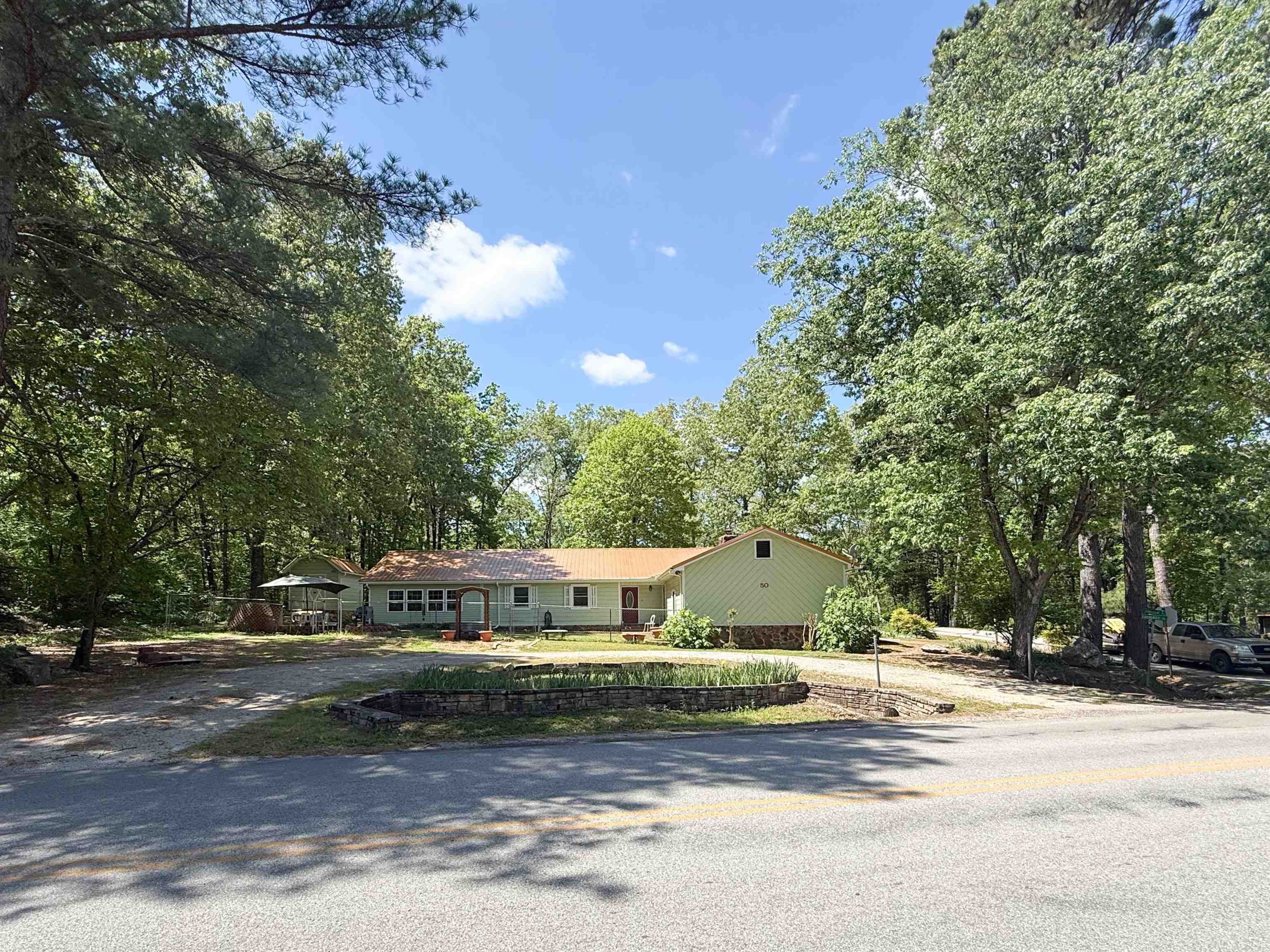 Custom Cherokee Village home on approx. 0.76 acres m/l, within walking distance to the South Fork of the Spring River. This well-maintained 3 bed, 2 bath home offers comfort, accessibility, and great outdoor living. Inside features a spacious living room with vaulted ceilings, real wood walls, a beautiful beam, and gas log fireplace, plus custom flooring throughout. The kitchen includes a bay window dining area and garden window over the sink for natural light.  The oversized master suite has vaulted ceilings and a large bath with walk-in shower plus direct access to the sunroom. A flexible office/bonus room connects to the laundry room with potential half bath hookups. A second bedroom also opens to the sunroom for great indoor-outdoor flow.  Wheelchair accessible with a 2-car garage and storage room. Outside is surrounded with landscaped views, multiple sitting areas, and a 600 sqft shop with RV hookups and lean-to. Ideal for full-time living, vacation, or investment.