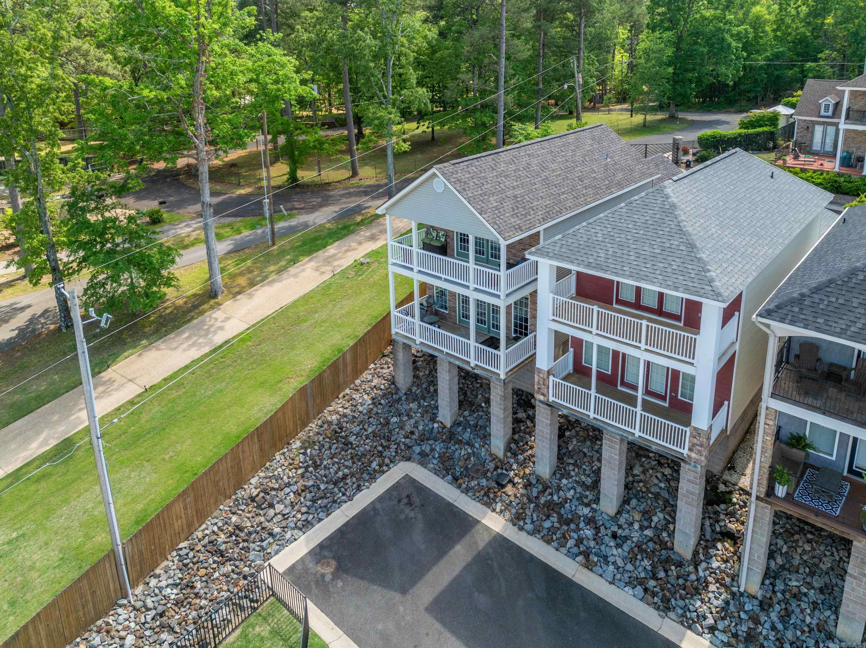 Welcome to lake living at its finest in the gated waterfront community of Majestic Lake Village on beautiful Lake Hamilton! This beautifully updated freestanding end-unit townhome offers the best of both worlds—the convenience of low-maintenance living with the privacy of a single-family home, including a fully fenced side yard that is perfect for pets, gardening, or simply relaxing outdoors. Step inside to discover a stunning open-concept floor plan filled with upscale finishes and designer touches. The main level features engineered hardwood floors, quartzite countertops and backsplash, stainless steel appliances, gas cooking, a cozy gas fireplace, updated cabinetry, and stylish fixtures throughout. Upstairs, both spacious bedrooms feature private en-suite baths, and the primary suite opens to its own covered balcony where you can wake up to breathtaking lake and mountain views. With two covered balconies, a two-car garage, and ownership of the land beneath the home, this property offers a rare combination of comfort, quality, and value. Residents of Majestic Lake Village enjoy gated security, a waterfront boardwalk, swimming dock, and common areas. See agent remarks for updates.