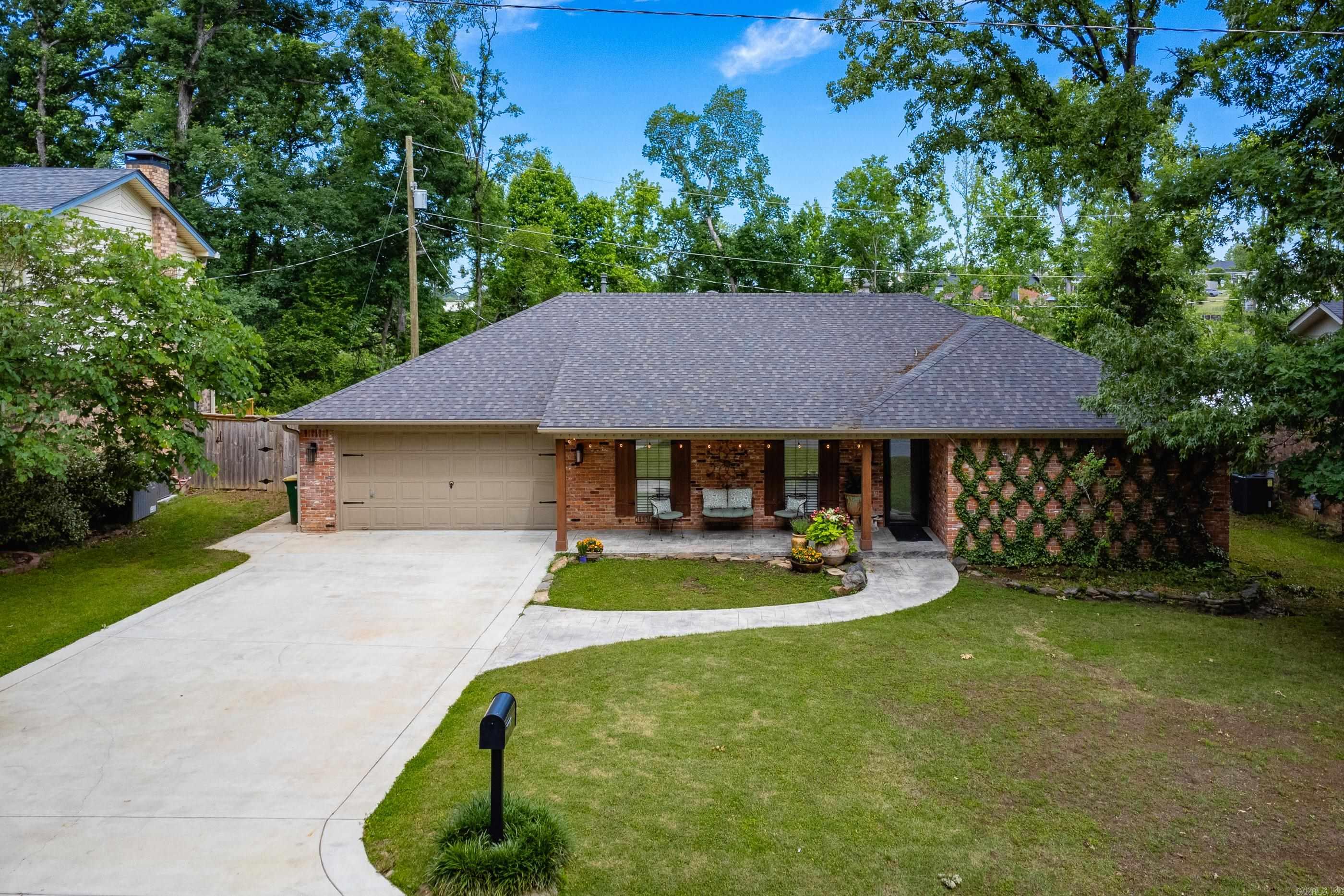Elegantly updated one level with quality detail and an eye for design. New roof 2023. Pull into an extra wide driveway to see a covered front porch with recessed lighting.  Enter through a custom glass front door to travertine floored living dining  combo that leads to large vaulted ceiling den with fireplace. Kitchen with stainless appliances and tile backsplash has eat in breakfast area.  Cabinets are first quality with adjustable shelves. Kitchen opens to butlers/bar area with storage and extra sink. Additional room with laundry hook ups can serve as office/hobby space.  Covered back porch is outdoor living haven with a swing daybed and plenty of room for grill and dining.  Home backs to green space. Antique columns were built in on brick base and were sourced from a Southen Plantation. Some interior doors were replaced with beautiful antique doors. 2 updated baths, hall bath has heated floors. Master has ample closet space.  Walk to park on path that enters on Kings Mountain.