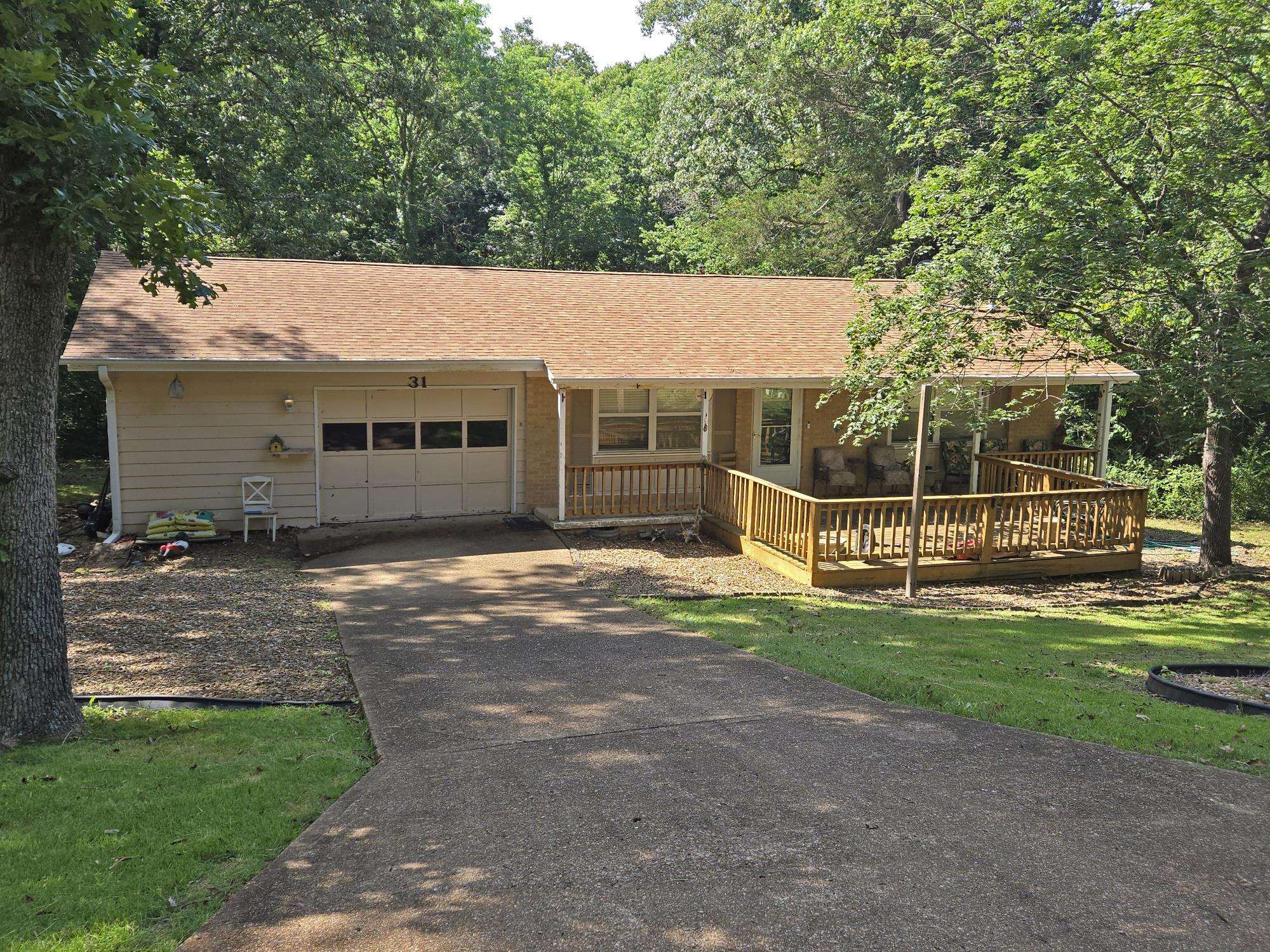 Comfortable, cozy, and updated, this 2 bedroom 1 bath brick home in the Village sits by itself on a low traffic street close to Town Center.  It has decks both front and back, drywall interior, laminate flooring in the living room, kitchen and bath, carpet in the bedrooms, updated kitchen cabinets and sink, 2022 architectural shingles, vinyl double pane windows, central gas heat and central air, gas log fireplace, one-car garage and 12x24 frame storage building suitable for creating your own workshop.  The stove, dishwasher, washer, dryer, built-in microwave and vinyl plantation blinds are included.  Nice front and back yards surrounded by trees.