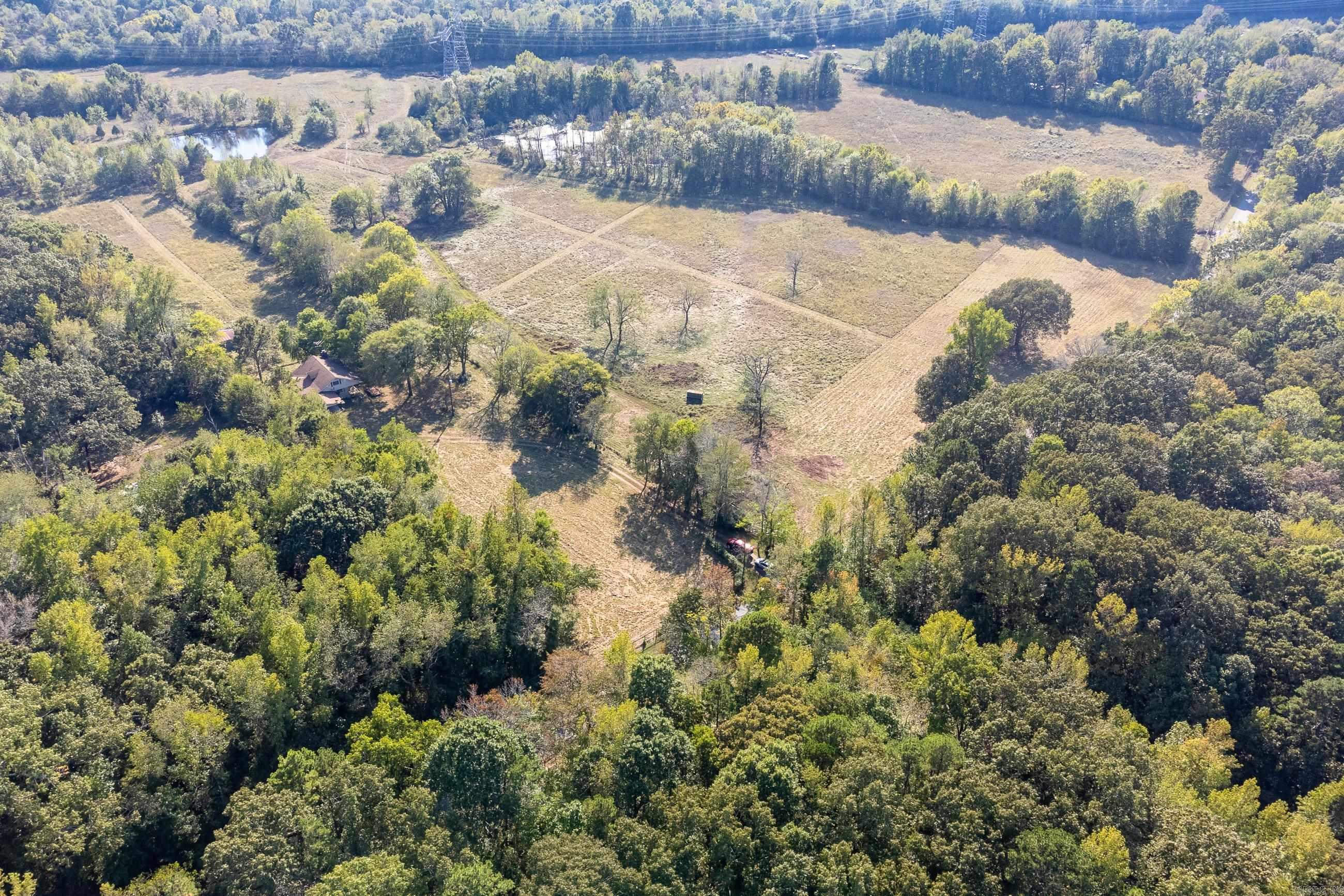 Wonderful flat 54 acres in West Pulaski County perfect for cattle or horses. Acreage is cleared & fenced w/ 2 ponds. Located in a grove of trees, the home has 4 bedrooms 2.5 baths, along w/ a formal living rm, den & hardwood floors. Home is perfect for a remodel or use as a guest house. Property also has a lrg shop & barn. Located 12 minutes from Chenal Parkway/Rahling Road & 15 minutes from I430.