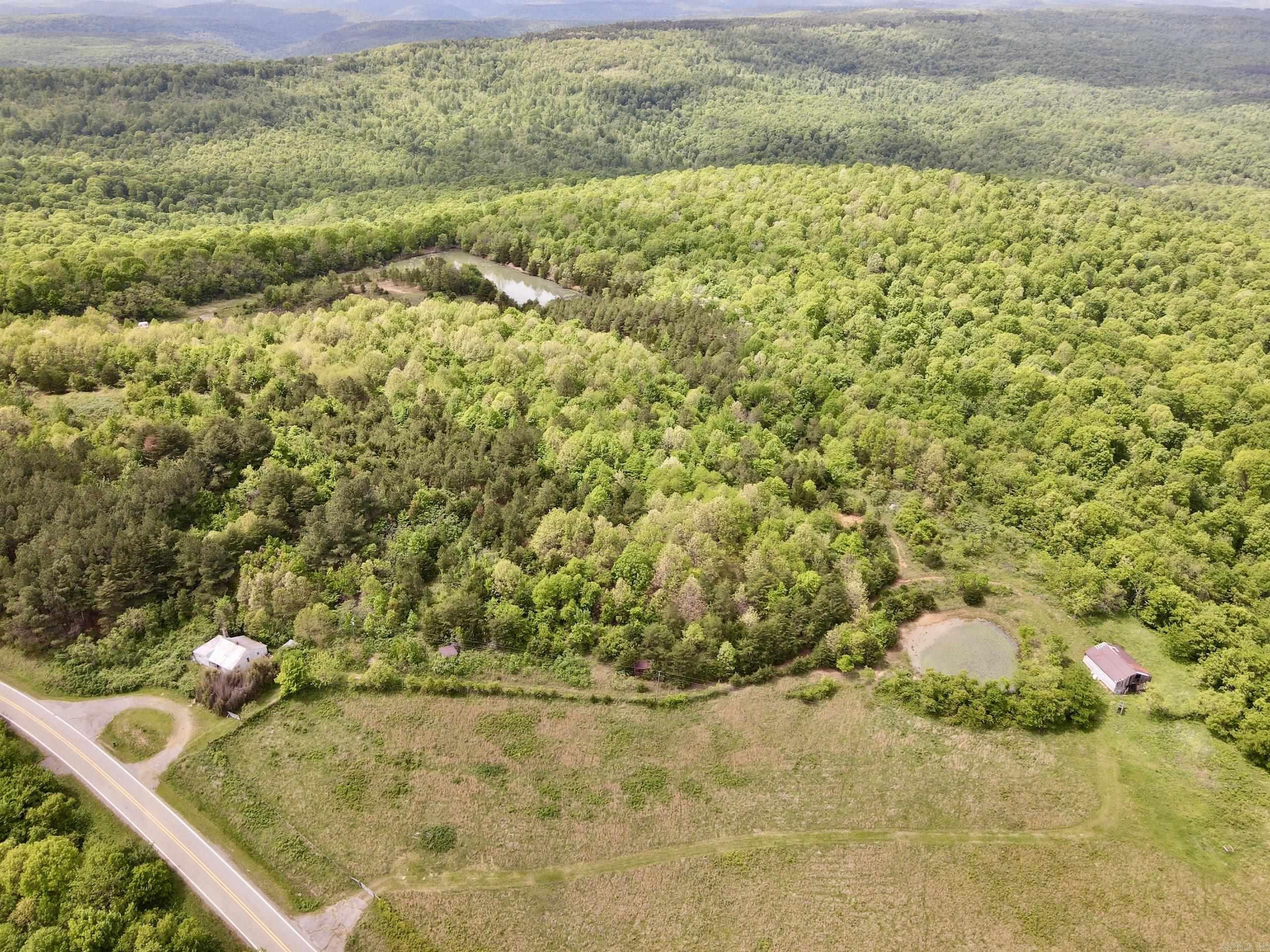 Properties like this are rare. This historic Ozark homestead, built in 1935, sits on a unique tract completely surrounded by the Ozark–St. Francis National Forest, offering unmatched privacy and direct access to thousands of acres of public land. The original home remains and could be refurbished into a cabin or retreat. With Highway 16 frontage and utilities available, the property combines accessibility with seclusion. Set along a ridge, it offers scenic views in multiple directions and several prime building sites. Water features include a flowing spring, two ponds, and a private stocked lake, providing exceptional recreational and long-term value. The land offers a mix of open pasture and mature timber, ideal for livestock, recreation, or enjoyment. The property supports deer, turkey, and black bear and is well-suited for hunting. It is fully fenced with gated access and includes an established trail system. A former rock quarry serves as a private shooting range. Mineral rights convey, making this an outstanding estate, farm, hunting, or legacy property.