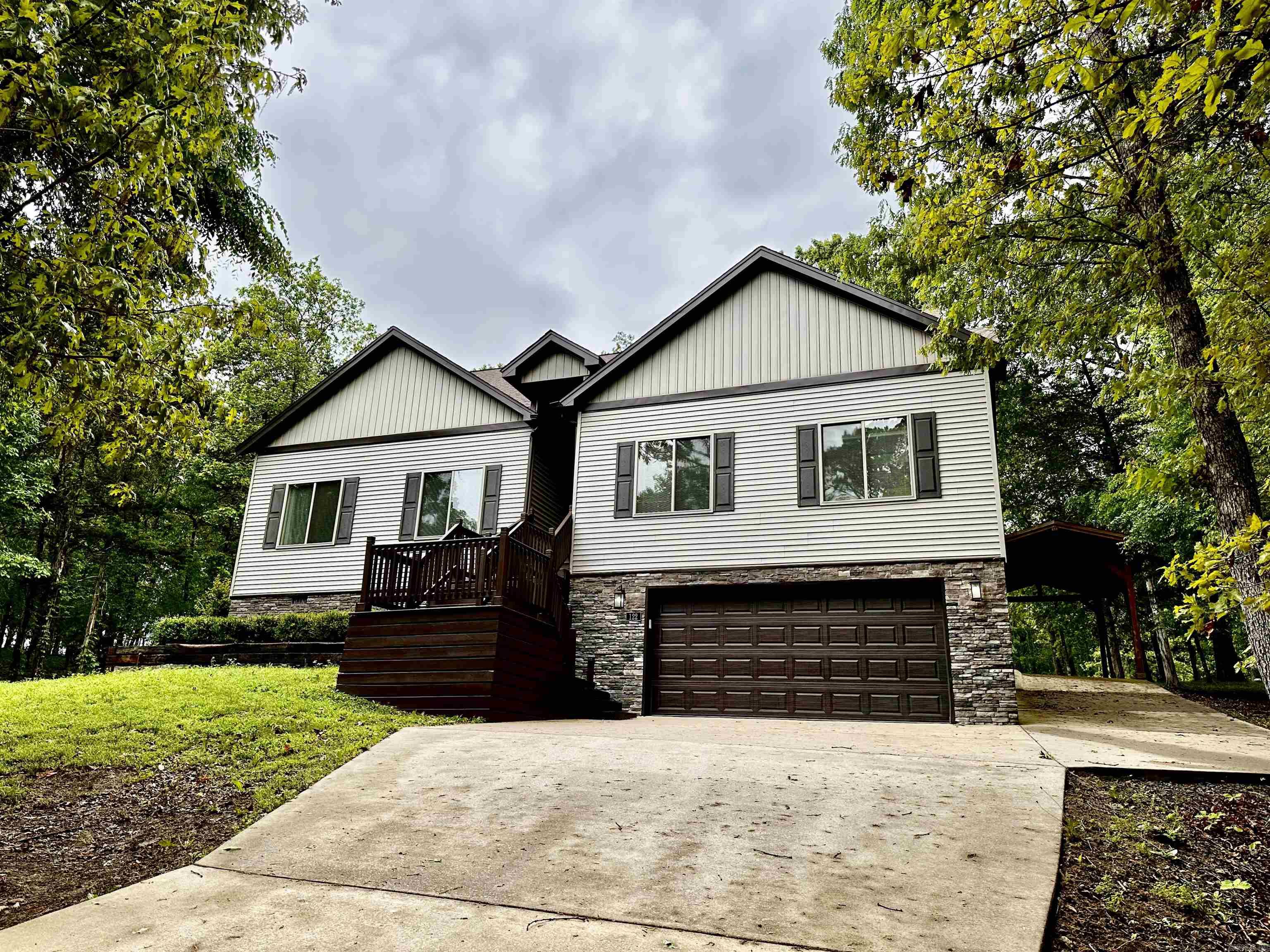 Welcome to 122 Crest Drive, Fairfield Bay, AR, a beautifully designed single-family residence nestled in the heart of Fairfield Bay. This property boasts 4 spacious bedrooms, a media room, 2 modern bathrooms and an expansive 2120 sq. ft. of living space, offering a perfectly blend of comfort and luxury. Open concept living, the seamless integration of the kitchen, dining, and living areas creates an inviting space for gatherings and daily living. The gourmet kitchen has granite countertops and ample cabinets, a large pantry and stainless appliances. The media room offers a dedicated space for movie nights or gaming sessions. The home also features an on-demand circulating hot water system. The double garage is located below the house, along with a large storage area, a separate carport has been added to the side of the home, off of the deck. Home is situated on the Indian Hills Golf Course on the 3rd hole. A large deck covers the back of the home so you can enjoy serene views and peaceful family gatherings. The property also includes a smart irrigation system. Lot to the south of property has been replatted and will convey with the property.