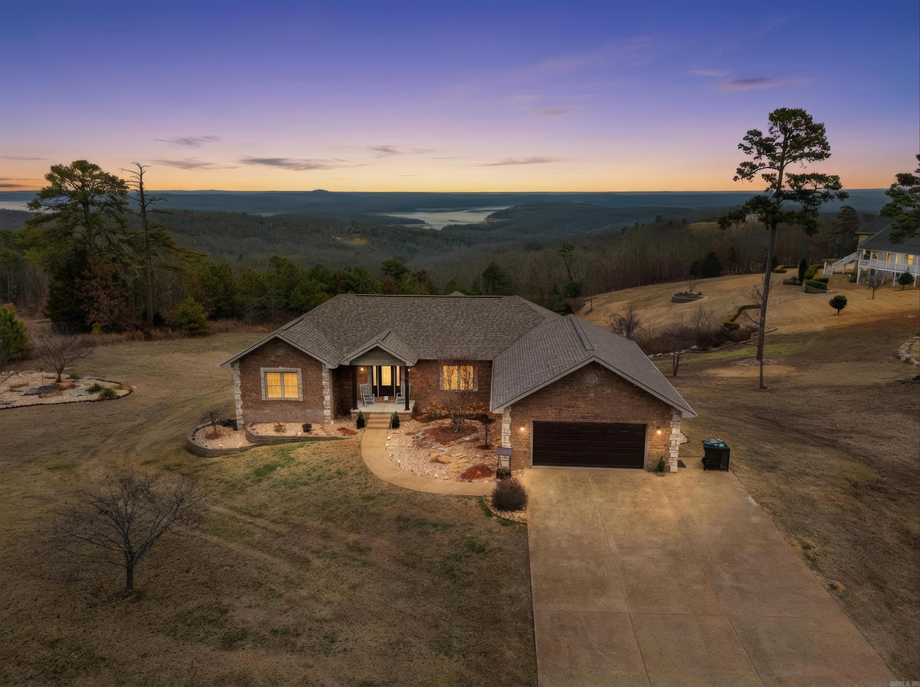 LAKE VIEWS & STUNNING SUNRISES. Nestled on 1.6 acres m/l in The Summit—known for large custom homes, underground utilities & NEXT high-speed internet—this all-brick 2006 home is just 5 minutes from Tracy Marina on Lake Norfork. Offering 5 bedrooms, 3 full baths & a finished walkout basement, there’s room for guests or multi-generational living. Updates include quartz island, remodeled primary bath with freestanding tub, fresh paint, lighting & landscaping. Major improvements: roof (2019), new appliances (2023) including heat pump & A/C, in-line hot water heater (2025) & a backup generator. Two gas fireplaces, built-in safe room & flexible lower level with exterior access. Home inspection complete + 14-month warranty offered. All appliances convey. Enjoy lake living every day.