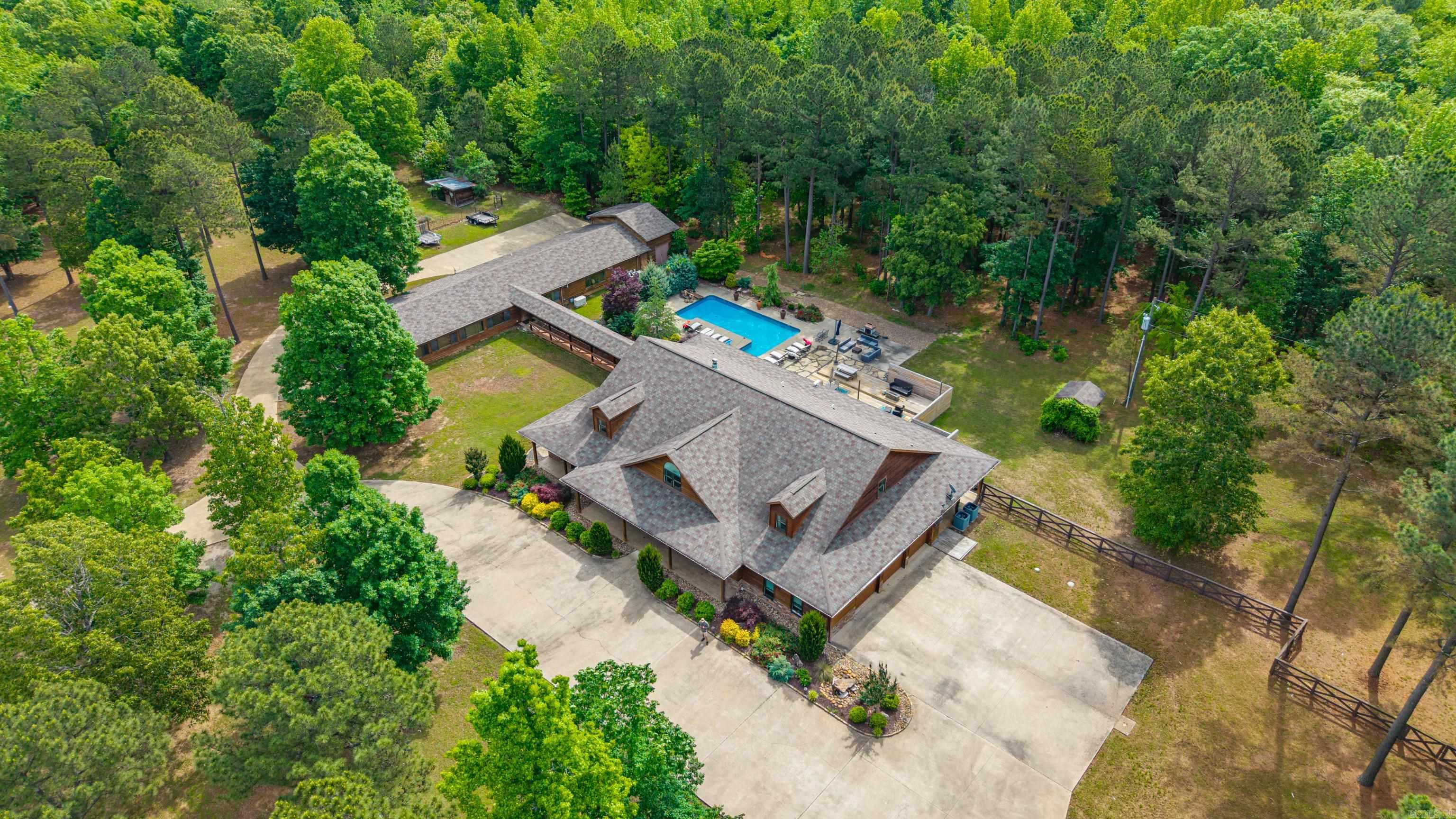 More than ten acres encompass 6,600 square feet of luxury living with this gorgeous two story home. Drive through one of the two gates past the picturesque pond and walk into the large living area that is the centerpiece of this home. Four bedrooms and three full bathrooms are downstairs, and a massive bonus area upstairs for a media room, game room, craft room, and/or home office, leave the possibilities endless. There is one full bath upstairs so an additional bedroom is an option. The enormous master closet is a showstopper with storage for absolutely everything you can imagine. The kitchen is well equipped with TWO dishwashers, a six burner gas stove, extra refrigerator, built-in ice maker and wrap around bar for plenty of seating. Enjoy the lush landscaping around the large patio that surrounds the captivating pool and hot tub. A full enclosed bath off the pool area. They even thought of your pets - with indoor built-in kennels and a tub for bathing your furry friends. An additional 1,800 square feet is located in a separate building with potential for a mother-in-law's quarters, a home gym or whatever your heart desires. Two three car garages. Must see property!