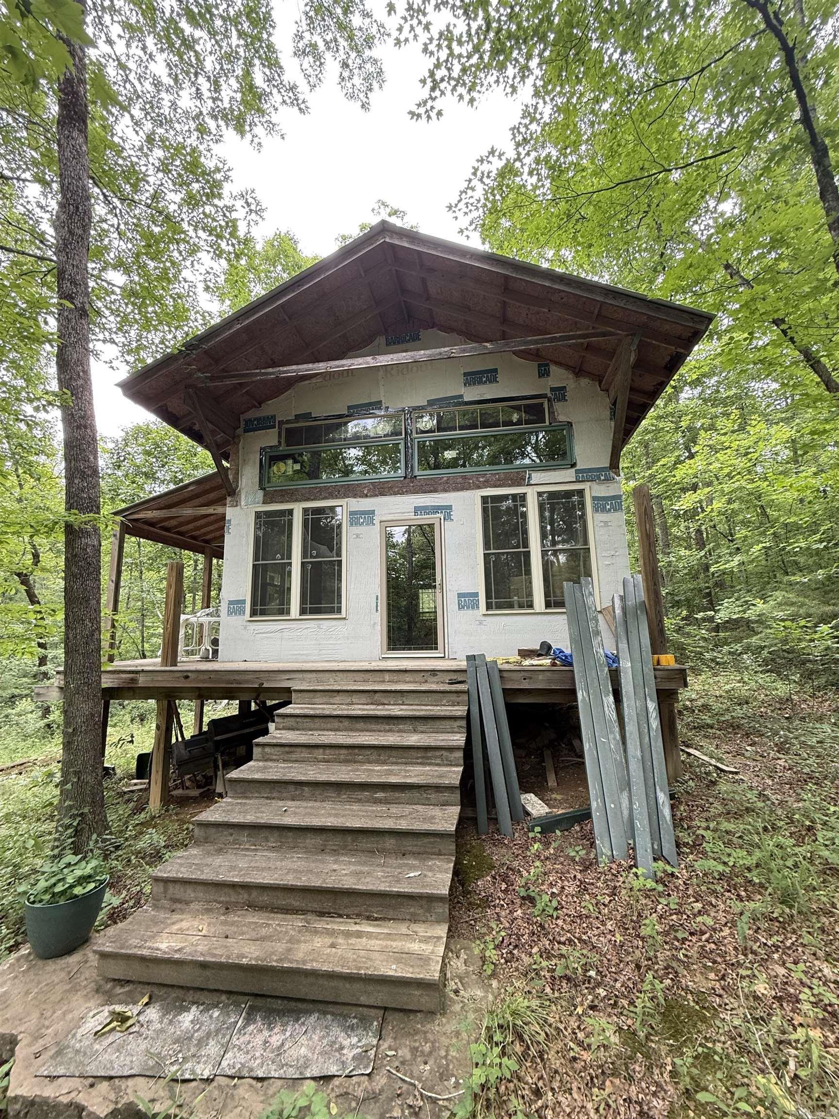 Escape to your own private retreat with this secluded 20-acre off-grid property! Nestled among the trees with a peaceful wet weather creek, this unique property offers the perfect setting for a hunting camp, weekend getaway, or future homestead. The 20x32 cabin is in the dry and features a wood-burning stove, providing a cozy place to relax and unwind. A private well is already in place, adding to the property’s self-sufficient appeal. Enjoy the beauty of nature, abundant wildlife, and the tranquility of country living while still having plenty of room to explore and make it your own. A rare opportunity to own a secluded slice of Arkansas paradise!  4WD required. AGENTS SEE REMARKS.