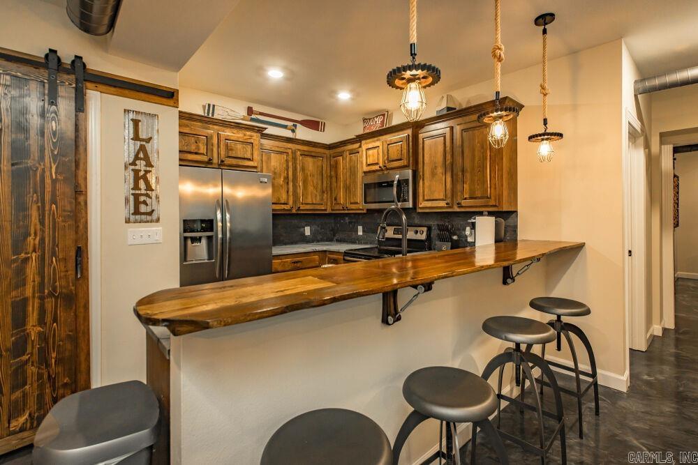 Suite 101 - First-floor unit in the Narrows Inn, one of nine lakefront condos offered at auction. This industrial-rustic 2 bed / 2 bath condominium (~1,181 SF) is built for entertaining with stained concrete floors, exposed ductwork, warm wood accents, and a built-in wine bar with cooler; pool views from the primary suite and guest bedroom. Kitchen features a live-edge wood bar top, Frigidaire stainless appliances, and solid-surface counters. Primary suite with sliding glass doors to the pool deck, walk-in closet, and double-vanity bath with large walk-in shower; guest bedroom and hall bath offer quality finishes. Pantry/laundry with GE stackable washer/dryer and barn-style doors. Offered through the Buyer’s Ultimate Choice auction with SOLDasap - bid on a single unit, any combination, or purchase all nine condos as a portfolio. Visit soldasap.com or call 870-236-6117 for full terms and conditions.