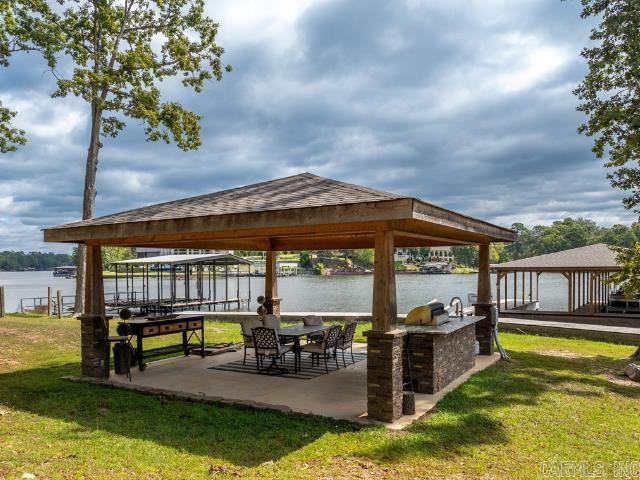 Looking for the perfect lakefront getaway and solid investment?  With 100 feet of Lake Hamilton frontage and a new 2-stall covered stationary boat dock, this home has everything you need for fun on the water and the fabulous outdoor kitchen offers the perfect setup for lakeside gatherings.    Inside there’s room for everyone with 4 bedrooms (each with lake view),  2.5 baths and a bonus/bunk room that could easily be converted to a game room.  Plus, the detached garage has been converted into additional living space that sleeps 6 with a kitchenette and full bath – perfect for additional guests or a private retreat.   Currently used as a short-term rental and offered fully furnished, this property is already set up to generate income while providing you the perfect spot for your own vacation days.  Whether you’re looking to invest or simply enjoy lake living, this one is a win-win! The adjacent lot with 98ft of lake frontage is also available for purchase and already has a boat dock.