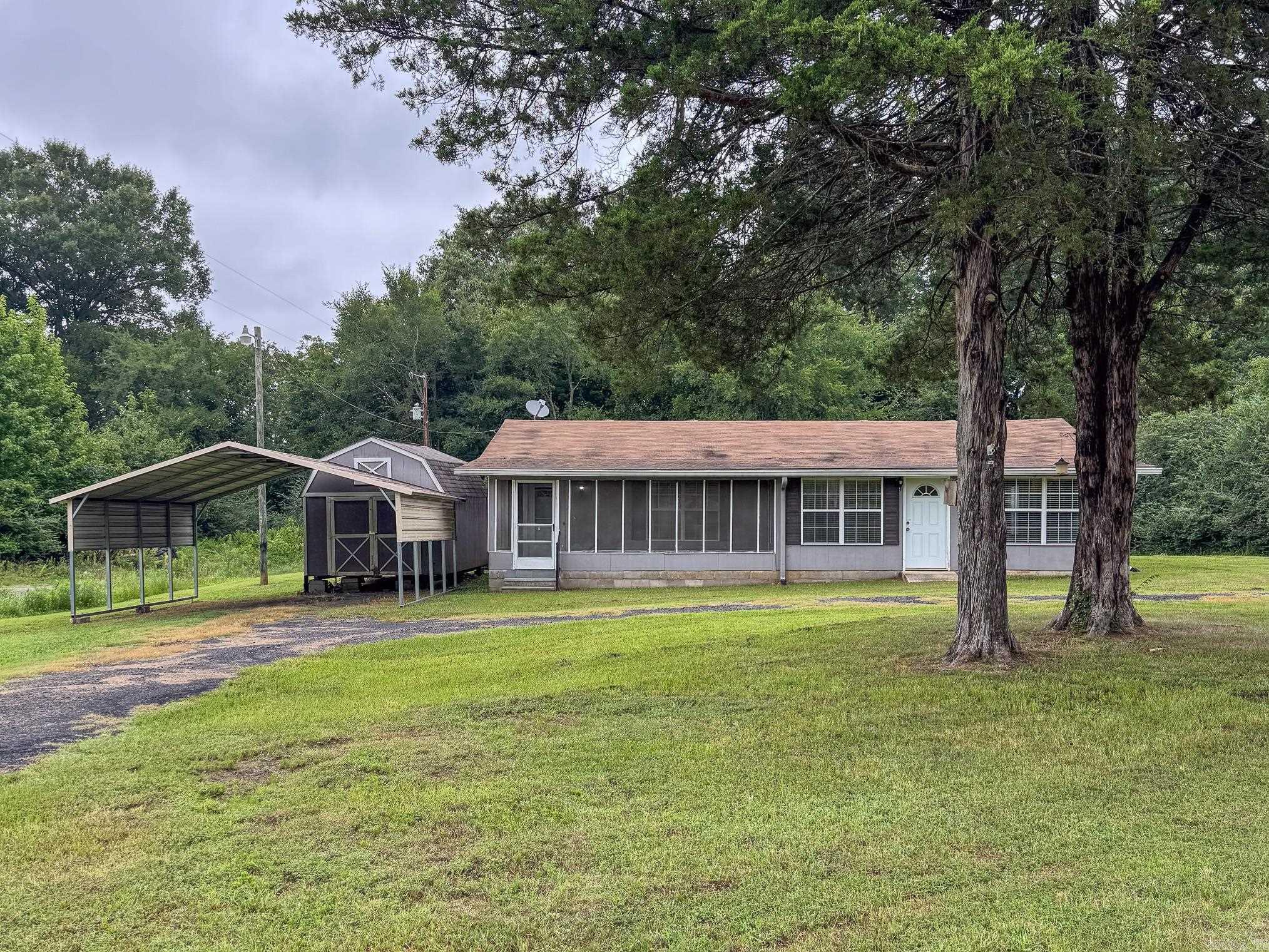 Great country living but still close to town. This home is currently being used as a 2 BR but could be converted back to a 3BR easily. Screened sunroom off the front entry and exterior door from bedroom. Refrigerator, washer and dryer stay. Also includes 2 car carport and 11x16 building with loft, all situated on almost 1/2 Ac lot. This property is ready for a new family. HVAC is approx. 2017. See agent remarks
