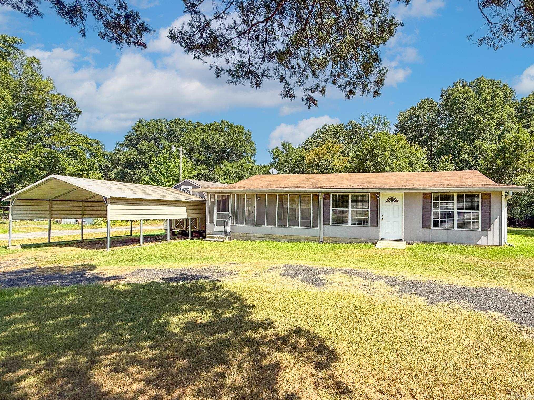 Great country living but still close to town. This home is currently being used as a 2 BR but could be converted back to a 3BR easily. Screened sunroom off the front entry and exterior door from bedroom. Refrigerator, washer and dryer stay. Also includes 2 car carport and 11x16 building with loft, all situated on almost 1/2 Ac lot. This property is ready for a new family. HVAC is approx. 2017. See agent remarks