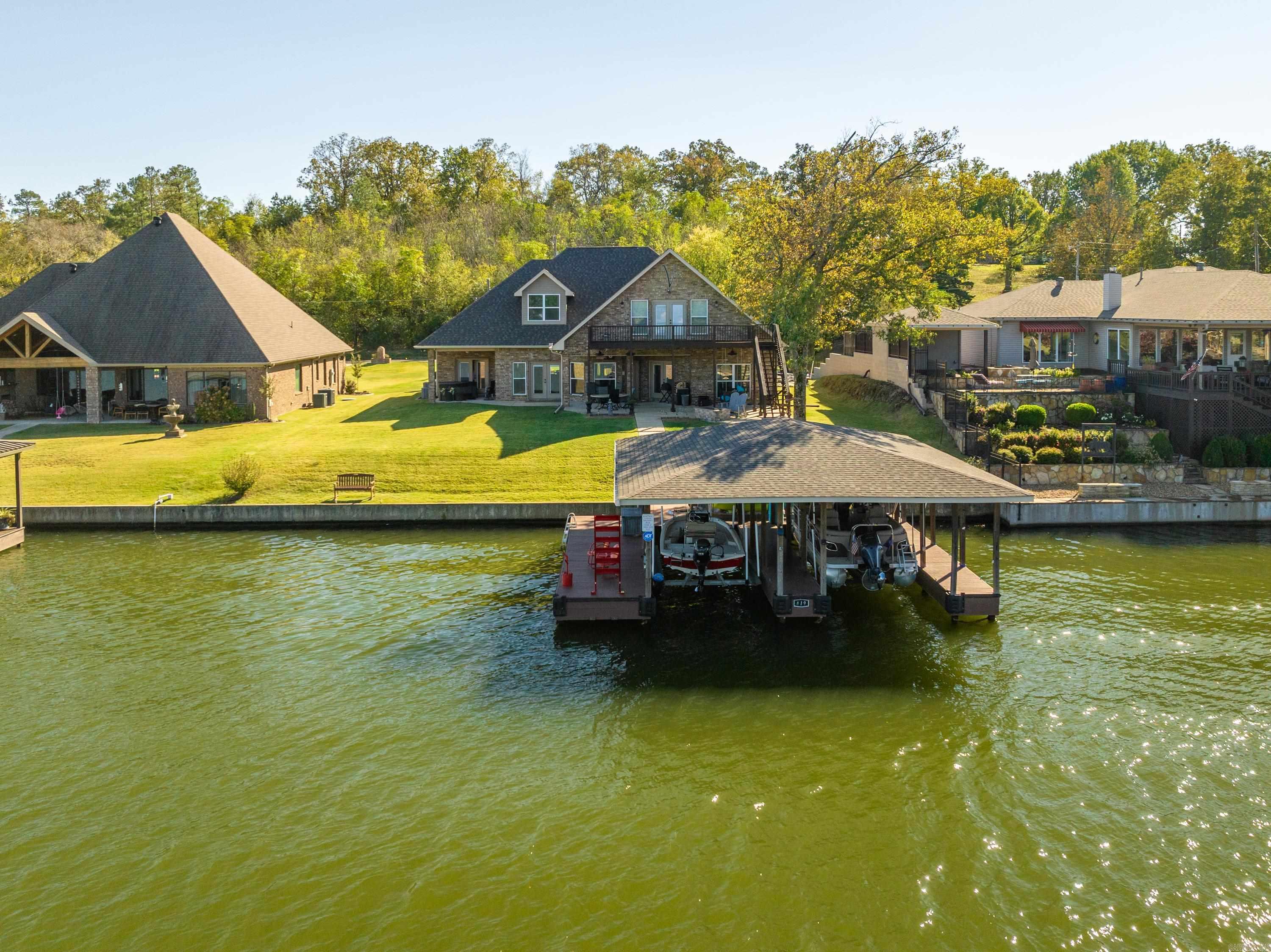 Experience the serenity of lakeside living with a perfect blend of elegance and waterfront living. A true haven for those seeking comfort, convenience, and view, this residence is a dream come true.  Just steps from your private shoreline, enjoy boating from your 2 stall covered boat docks with lifts. Gather around the custom fire pit, unwind on the covered patio or relax in your own hot tub. The main level will encourage you to stay at home with view of the lake from everywhere. The upstairs features it own private living space, private bedroom and bath, and an outside deck with access to the lake.  The lot is level, providing a perfect canvas for landscaping and outdoor activities.  Your dream lakefront home awaits-don't let this one slip away !!!