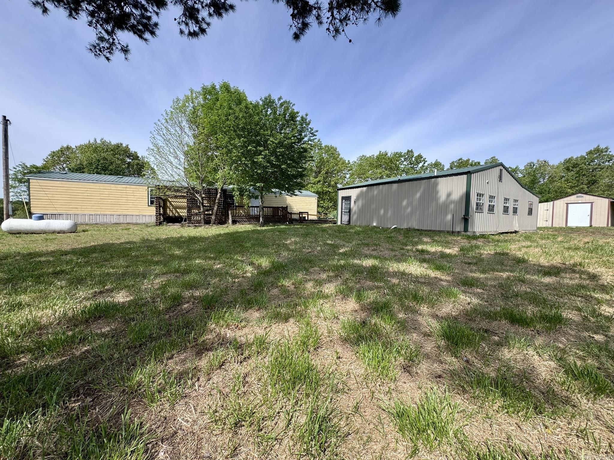 This property resides on 4.97 acres in the Pine Tree 2nd Addition subdivision of Oxford, Arkansas. It offers a 2-bedroom, 2-bathroom manufactured home with 1,008 square feet of living space, along with a versatile barndominium-style livable shop that includes 2 bedrooms, 1 bathroom, and 896 square feet. This unique setup provides excellent flexibility for guests, extended family, or potential rental income.  The property features an in-ground manufactured storm shelter, a large yard, a scenic pond, and a lawn mower shed with a lean-to for additional storage. Whether you're looking for a multi-use property, a small homestead, or a country home with room to spread out, this listing offers it all for only $129,900.
