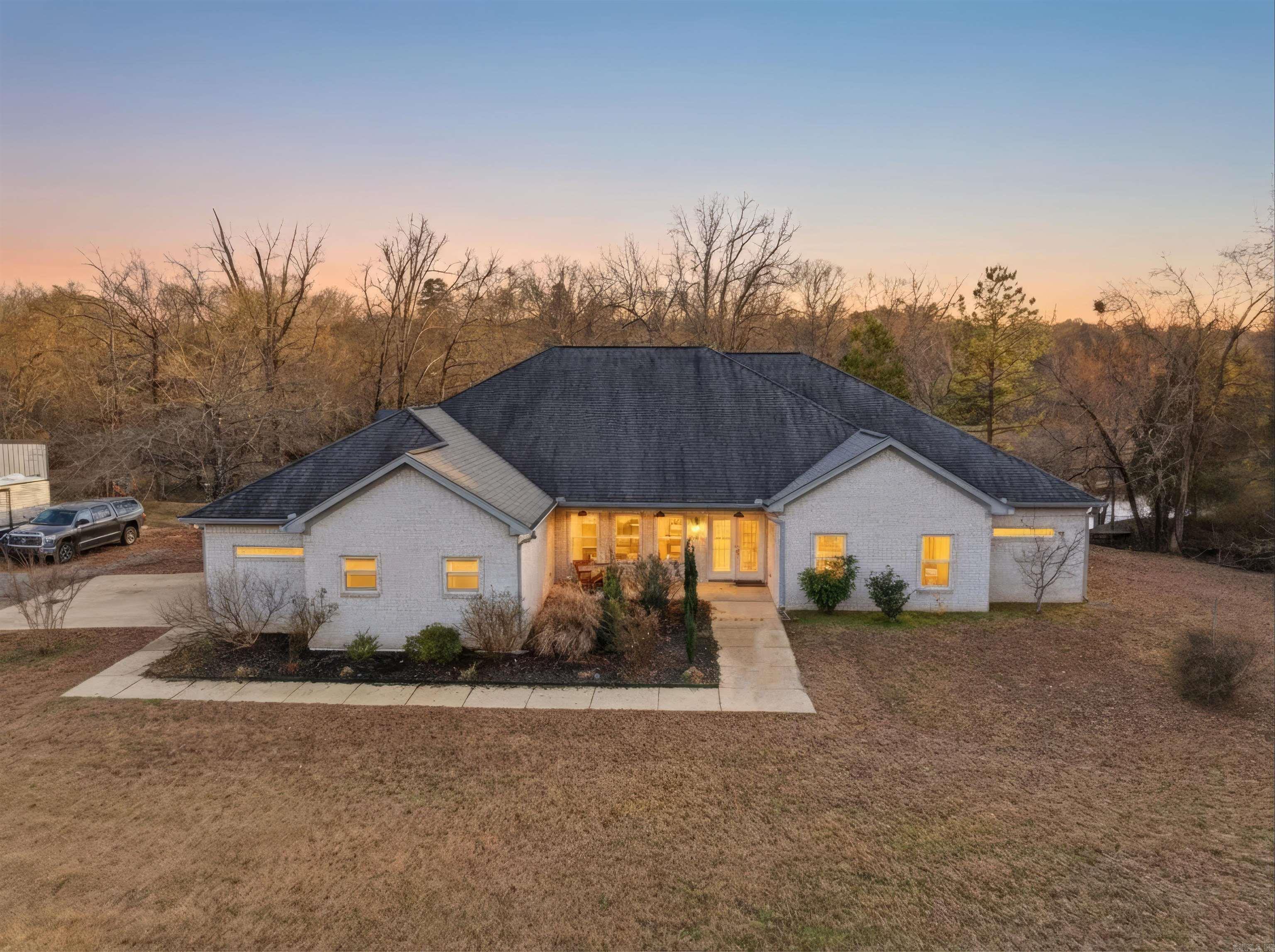 This custom-built, single-level waterfront home offers 3 bedrooms and 3.5 bathrooms, along with a formal dining room, spacious eat-in kitchen, and a bright sunroom designed to capture serene views. With a total of four garage spaces, there is ample room for vehicles and storage. The well-appointed kitchen is a chef’s dream, featuring two stoves, three ovens, abundant cabinetry, a large island, and a walk-in pantry. The primary and guest bathrooms both include heated floors for added comfort. The laundry room is generously sized, complete with space for a refrigerator with an ice-maker connection, and is conveniently located near the attached side-loading two-car garage. In addition to the main residence, a 40x60 shop provides exceptional versatility. It includes a two-car garage, a half bathroom with two sinks, a storage room, and private guest quarters offering one bedroom, one bathroom, a kitchen, living area, and washer/dryer space (guest quarters square footage not included in the 3,071 sq. ft. main home). Situated on just over three acres along the Mazarn River and Lake Hamilton, this property offers peaceful waterfront living with abundant wildlife and picturesque views right