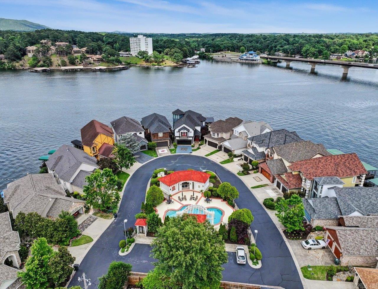 Experience luxury lake living at its finest in the prestigious Paradise Lake Village. Situated on one of the most iconic and recognized points on Lake Hamilton, 333 Paradise Point is an exquisite tri-level waterfront retreat offering breathtaking east facing main channel views and unforgettable sunrises. Dramatic walls of windows fill the home with natural light while showcasing million-dollar views from nearly every room. Designed with sophisticated style this home offers an expansive open concept kitchen ideal for entertaining, 3 fireplaces, and seamless indoor-outdoor lake living. The entire third floor is dedicated to a private primary suite sanctuary featuring an oversized bedroom retreat, expansive spa-style bath, massive walk in closet, a versatile flex room, and convenient laundry hook ups. The lower level offers an ideal guest or entertaining retreat featuring a separate living area, kitchenette, two bedrooms with private bathrooms, and additional laundry hook ups. Patio doors lead directly to the lakeside patio and covered boat slip for effortless waterfront living. A rare opportunity to own a fashionable, one of a kind Lake Hamilton property in an extraordinary setting.