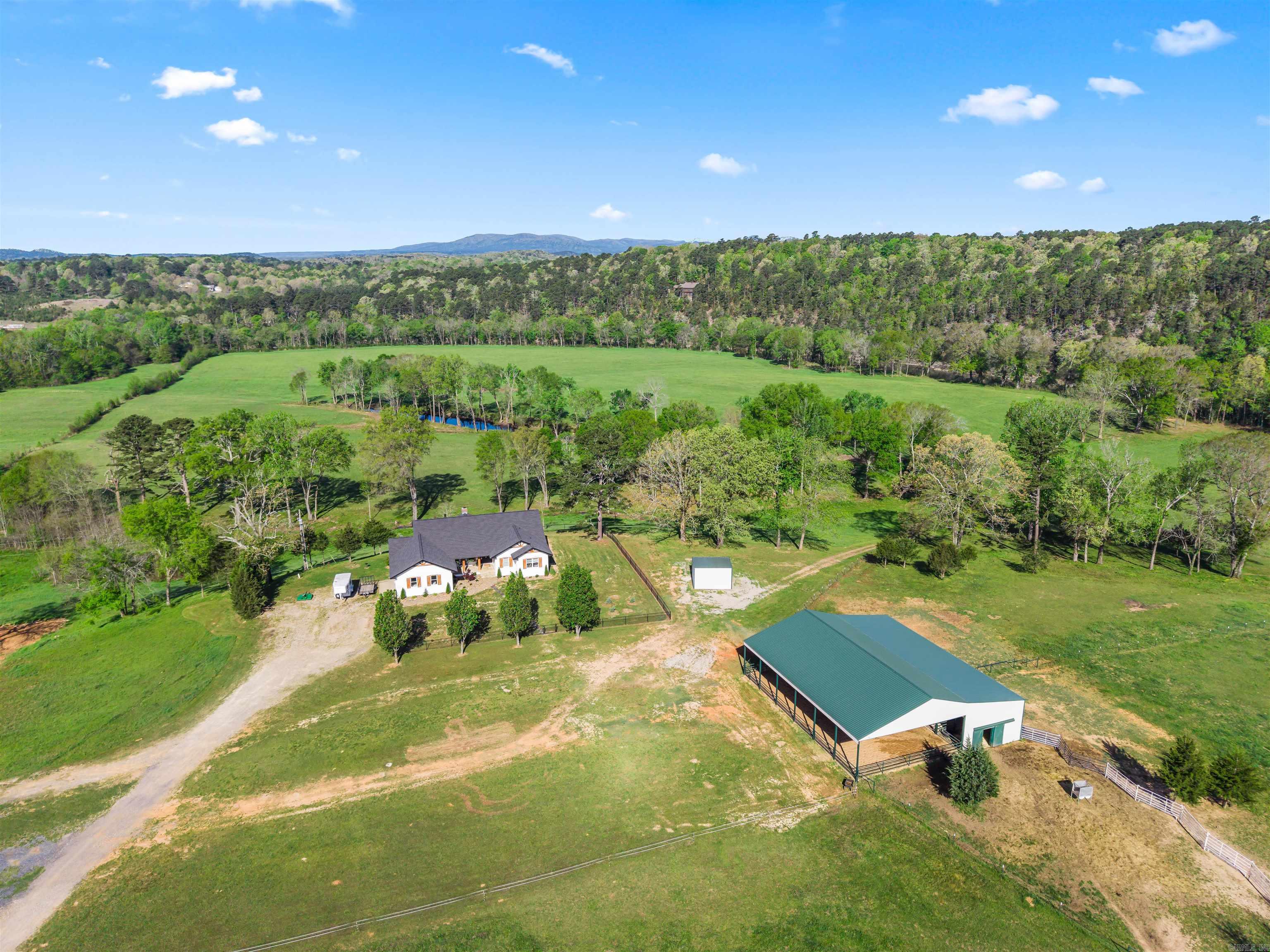 Pass through the stone-pillared automatic gate and discover one of Arkansas's most extraordinary riverfront estates. Spanning 81.87 acres with thousands of feet of Ouachita River frontage, this exceptional property features **two beautifully finished luxury residences**, a third residence ready for completion, and a newly built equestrian facility—all surrounded by rolling cross-fenced pastures, wooded bluffs, breathtaking Ouachita Mountain views, and unmatched privacy. The completely remodeled 2024 main residence offers 6 bedrooms, 3.5 baths, soaring cathedral ceilings, a dramatic native stone fireplace, chef's kitchen, and expansive outdoor living. A separate luxury 2-bedroom, 2-bath barndominium provides exceptional guest accommodations or income potential, while the private walk-out guest residence and unfinished 2,800-square-foot barndominium add even more flexibility. Complete with a 2024-built horse barn featuring 4 stalls, tack room, wash bay, hay storage, and covered riding area, this is a truly rare Arkansas legacy property.