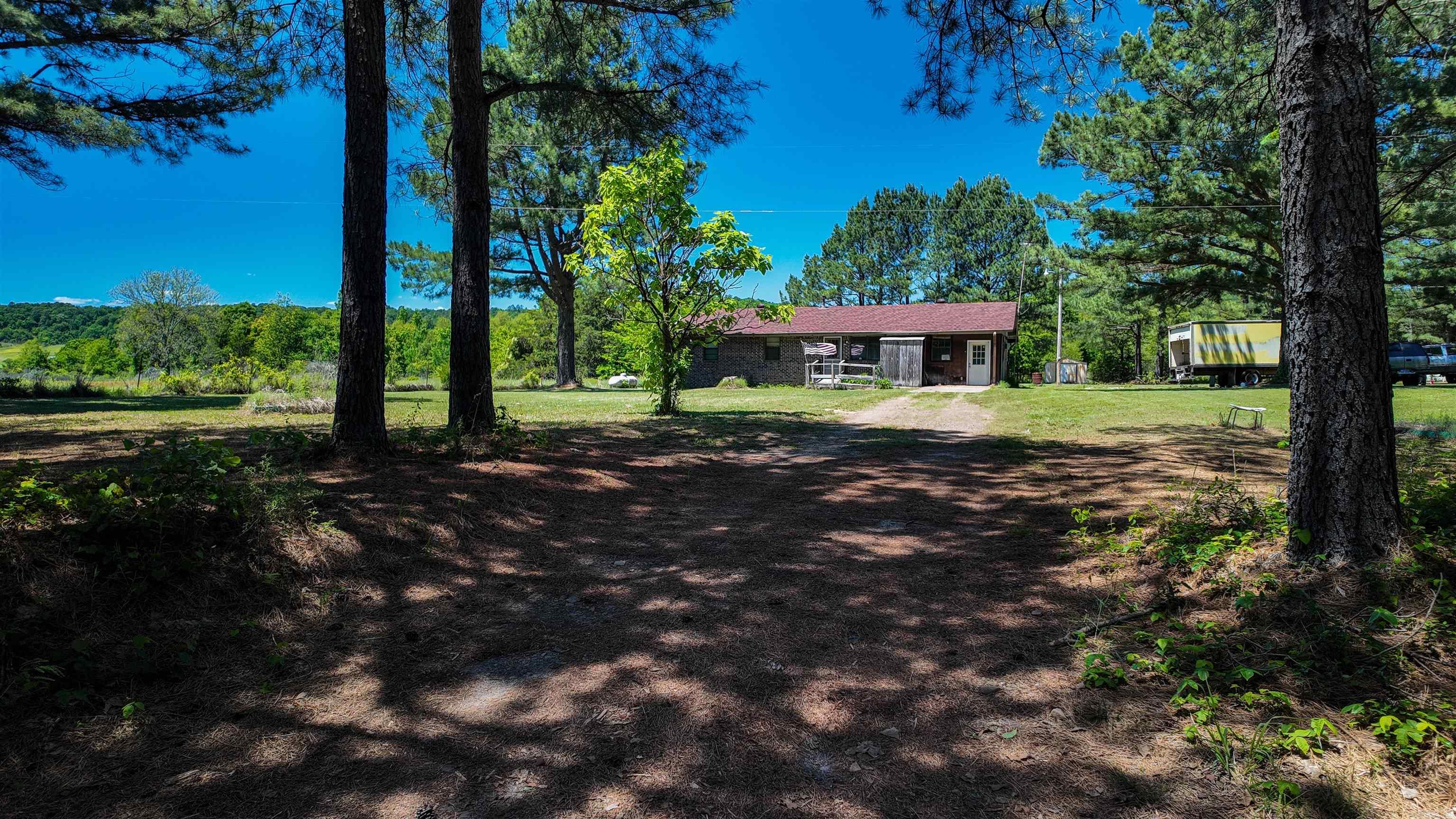 Charming country home situated on approximately 1 acre in the peaceful Center Ridge area! This one-level brick home offers rustic character throughout with warm wood accents, spacious living areas, a cozy fireplace, and a separate laundry room for added convenience. Originally a 3-bedroom home, one bedroom was combined to create an enlarged primary bedroom with additional space and comfort. Recent updates include a roof replacement and installation of a central HVAC system approximately 3 years ago. Enjoy relaxing mornings and evenings from the large covered porch overlooking the scenic rural setting. The property also features an attached storage/work area with concrete flooring, a storage building, concrete driveway, and plenty of outdoor space to enjoy country living while still being conveniently located to surrounding communities.