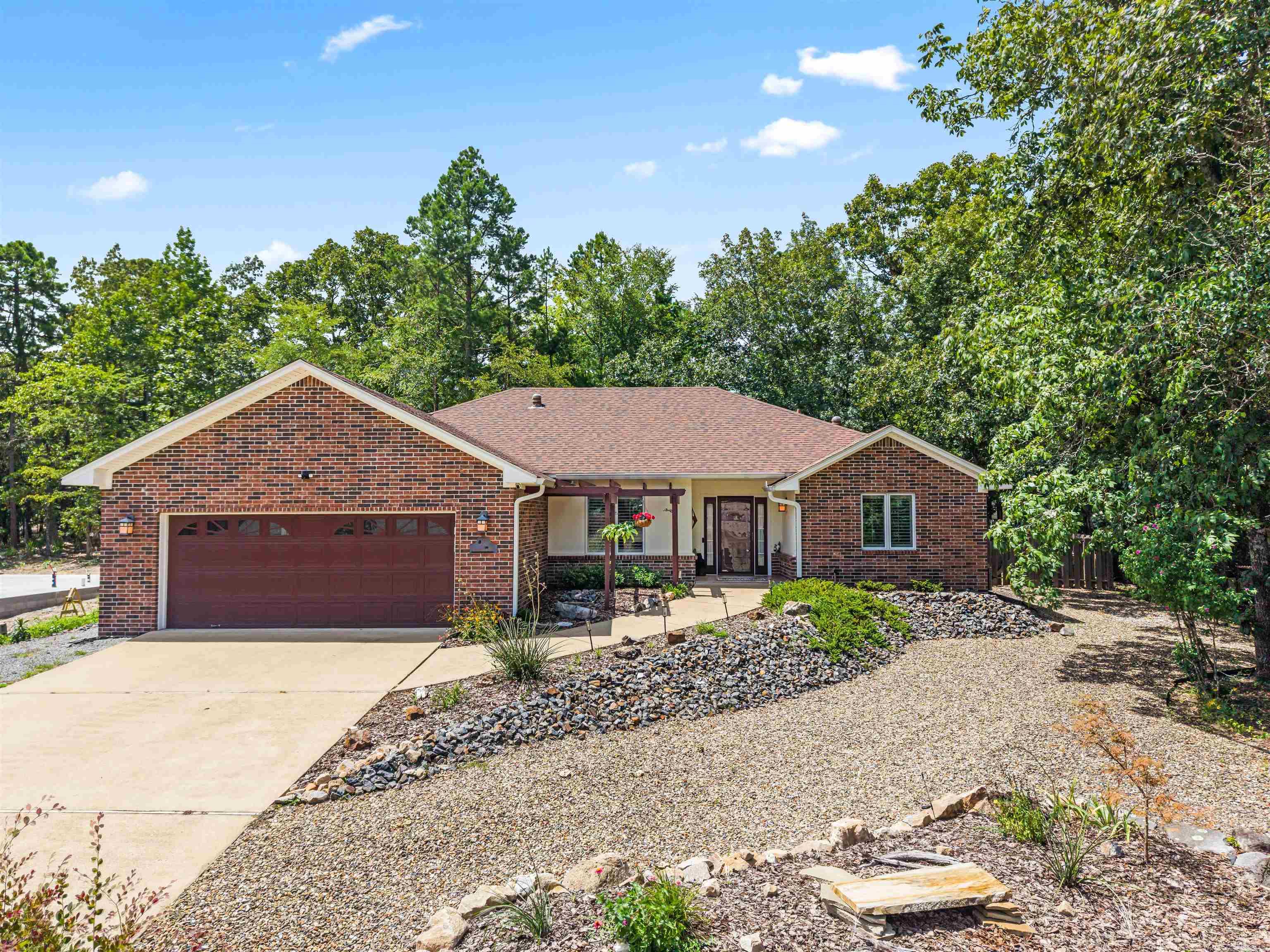 Low-maintenance brick home in a quiet, single-entry subdivision on the east side of Hot Springs Village. The carpet-free layout features luxury vinyl plank flooring throughout the living areas and all 3 bedrooms, with tile flooring in the bathrooms. The interior offers a split-bedroom design for privacy. The main living room features 9-foot ceilings, an updated fireplace, and large picture windows for natural light. The kitchen is equipped with stainless steel appliances and connects to a separate dining room. The breakfast room overlooks the private, wood-fenced backyard. A separate laundry room provides a utility sink, pantry, and extra storage. The primary suite features a tray ceiling, sliding door access to the patio, an updated walk-in shower, a walk-in closet, and a separate toilet closet. Outside, the property includes professional landscaping, a patio suited for birdwatching, and a separate deck for grilling. Includes an attached 2-car garage with extra depth for storage. Roof replaced in 2021. See the attached sheet for a complete list of updates.