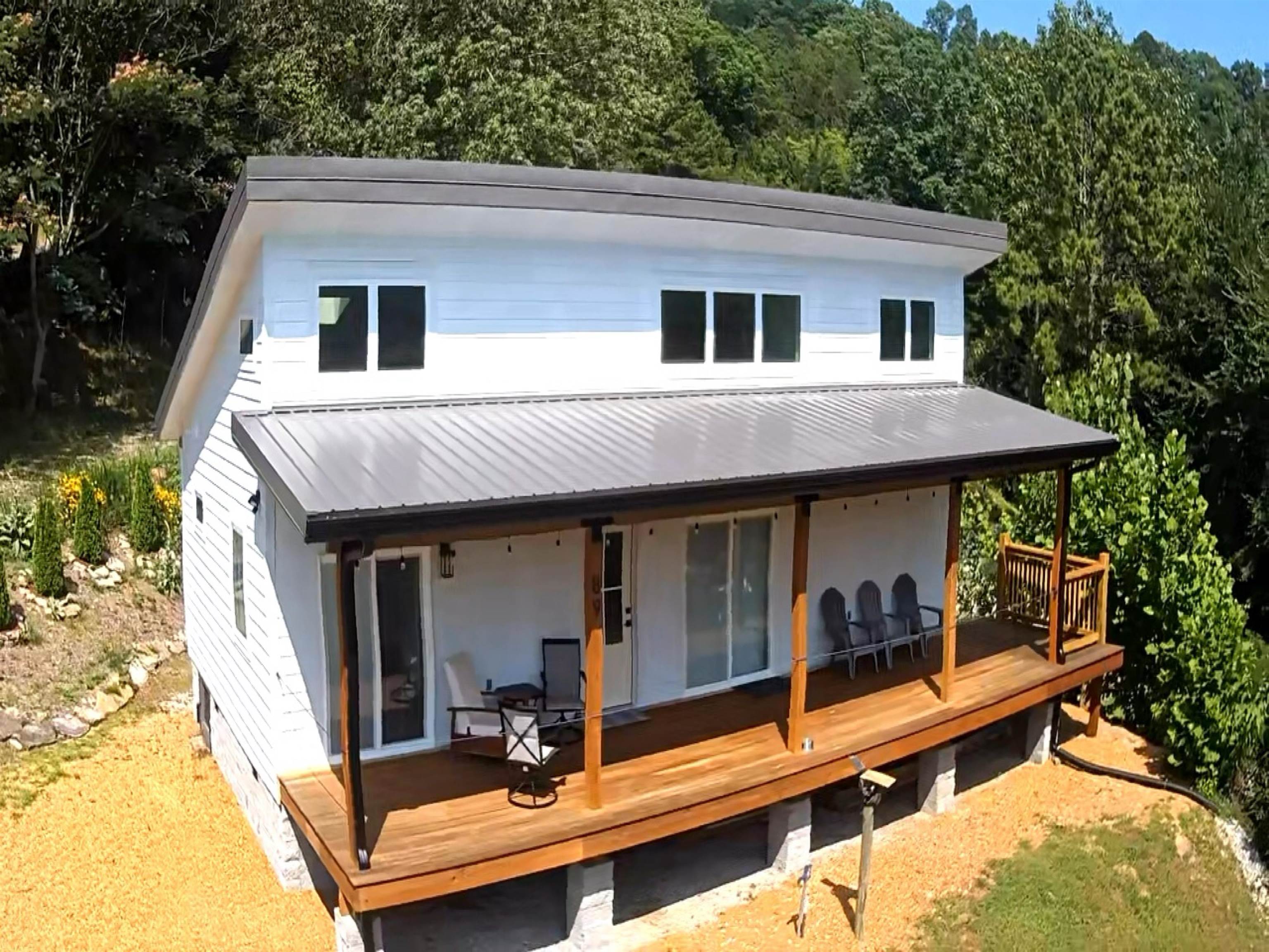 Modern mountain living meets low-maintenance simplicity in this custom-built retreat nestled in the Ozarks. Designed with clean architectural lines and soaring ceilings, this thoughtfully crafted home offers an open-concept layout filled with natural light, contemporary finishes, and a warm modern aesthetic. The kitchen features stainless appliances, a gas range, and attractive finishes, flowing seamlessly into the living area with dramatic ceiling heights and access to the expansive 10 x 45 covered deck—perfect for relaxing, entertaining, or enjoying the surrounding natural beauty year-round. Situated on 3.04 acres with a private gated entrance, the property includes landscaped grounds with native stone accents, two storage containers that convey, and a prepared site for a future shop, garage, boat storage, or additional outdoor living space. Additional features include a metal roof, mini-split heating and cooling system, and low-maintenance exterior. Minutes from the White River boat launch and outdoor recreation, this newly built home offers the perfect blend of comfort, style, and Ozark beauty. Call for your tour now!