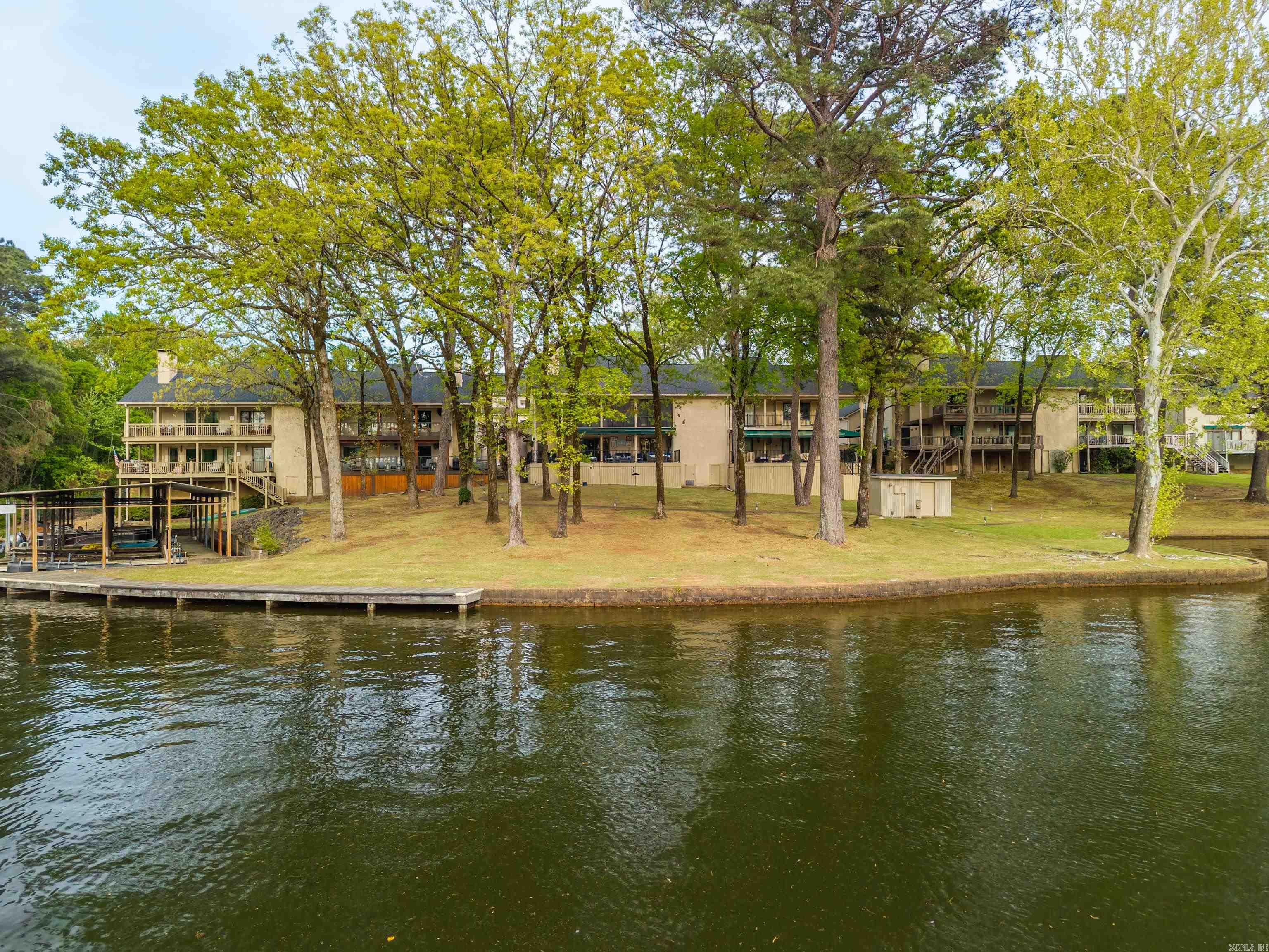Exquisite Lakeside Living! Renovated Townhome with Premium Amenities. Experience the perfect blend of luxury and leisure in this stunning, completely updated lakefront townhome.  This home is designed for those who want the best of lake life without the maintenance. A thoughtfully designed 3-bedroom, 3-bathroom floor plan, providing privacy and comfort for family and guests alike. The heart of the home features a large site-built fireplace, adding warmth and architectural character to the living space. Relax on the screened-in porch or enjoy the open air with the convenience of a retractable awning, perfect for controlling your shade on sunny afternoons. Forget the hassle of off-site storage. This property is rare for condo living, providing a large (23'x23') 2 car garage for vehicles, water toys, and gear. It has a Covered Boat Dock with lift. The well maintained grounds feature a tennis court and a large pool. Whether you are looking for a full-time residence or a premier vacation getaway, this condo delivers on every front.