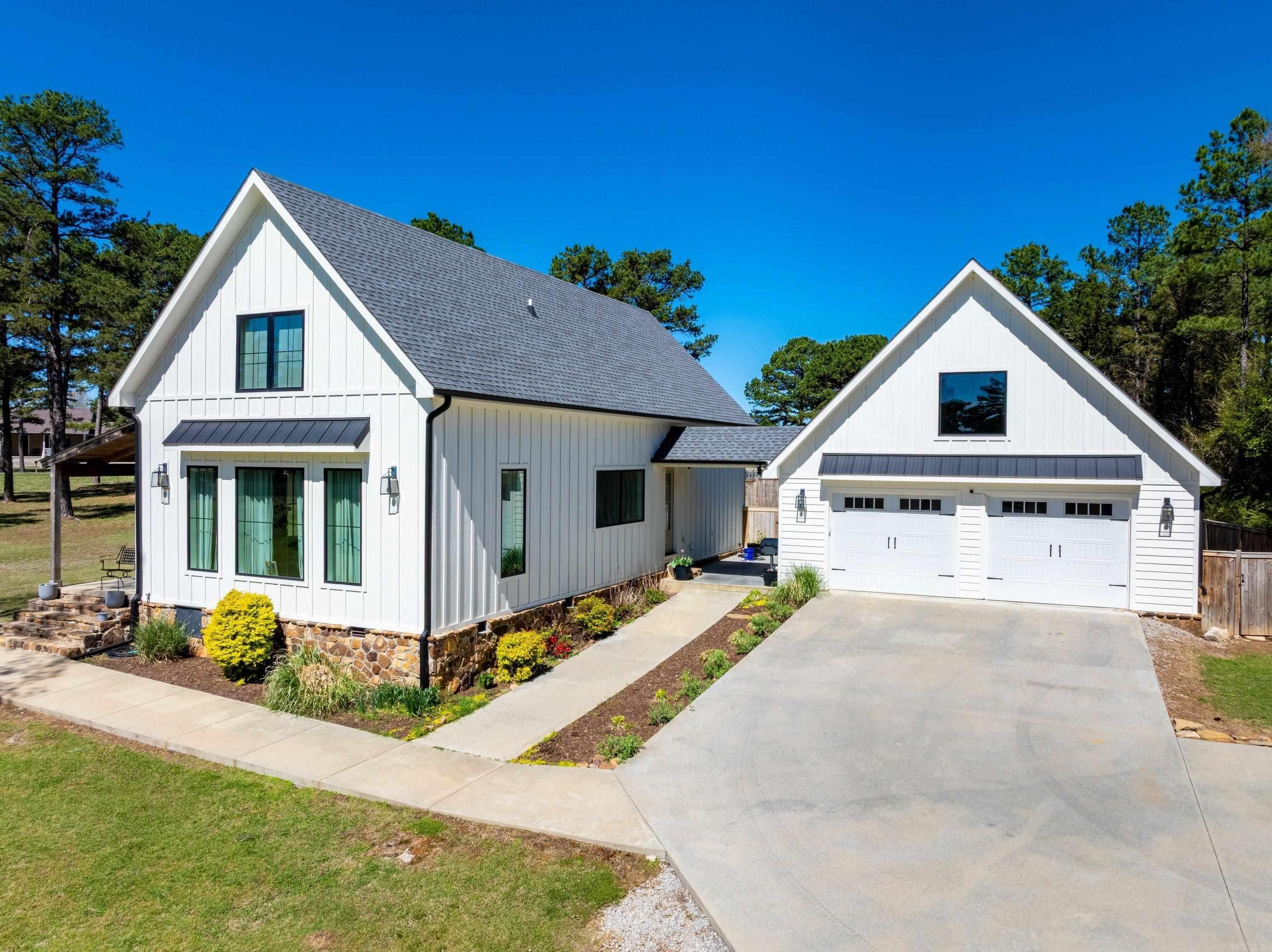 Welcome to this beautiful modern farmhouse-style home in one of Cave City’s most desirable neighborhoods—Double Oaks Estates, also known as the Patterson Subdivision. This peaceful, well-kept community offers pride of ownership, a true neighborhood feel, and a charming lake where residents enjoy fishing, watching geese, or relaxing by the water. Situated at the end of a cul-de-sac, this 2,588± sq ft home offers exceptional privacy with woods bordering one side and a privacy-fenced backyard ideal for kids, pets, and entertaining. The home features 4 bedrooms and 3 bathrooms with a thoughtful, family-friendly layout. The main level includes a spacious living room open to the dining area and kitchen, a large pantry, laundry room, primary suite, an additional bedroom, and a guest bath. Upstairs are two more bedrooms and a full bath. Enjoy outdoor living from the welcoming front porch, a fire pit area, and both indoor and outdoor electric fireplaces, plus a gas fireplace inside for cozy evenings. Additional highlights include custom cabinetry, 10-foot ceilings on the main level, beautiful landscaping, and a detached two-car garage with an unfinished, insulated bonus room above garage.