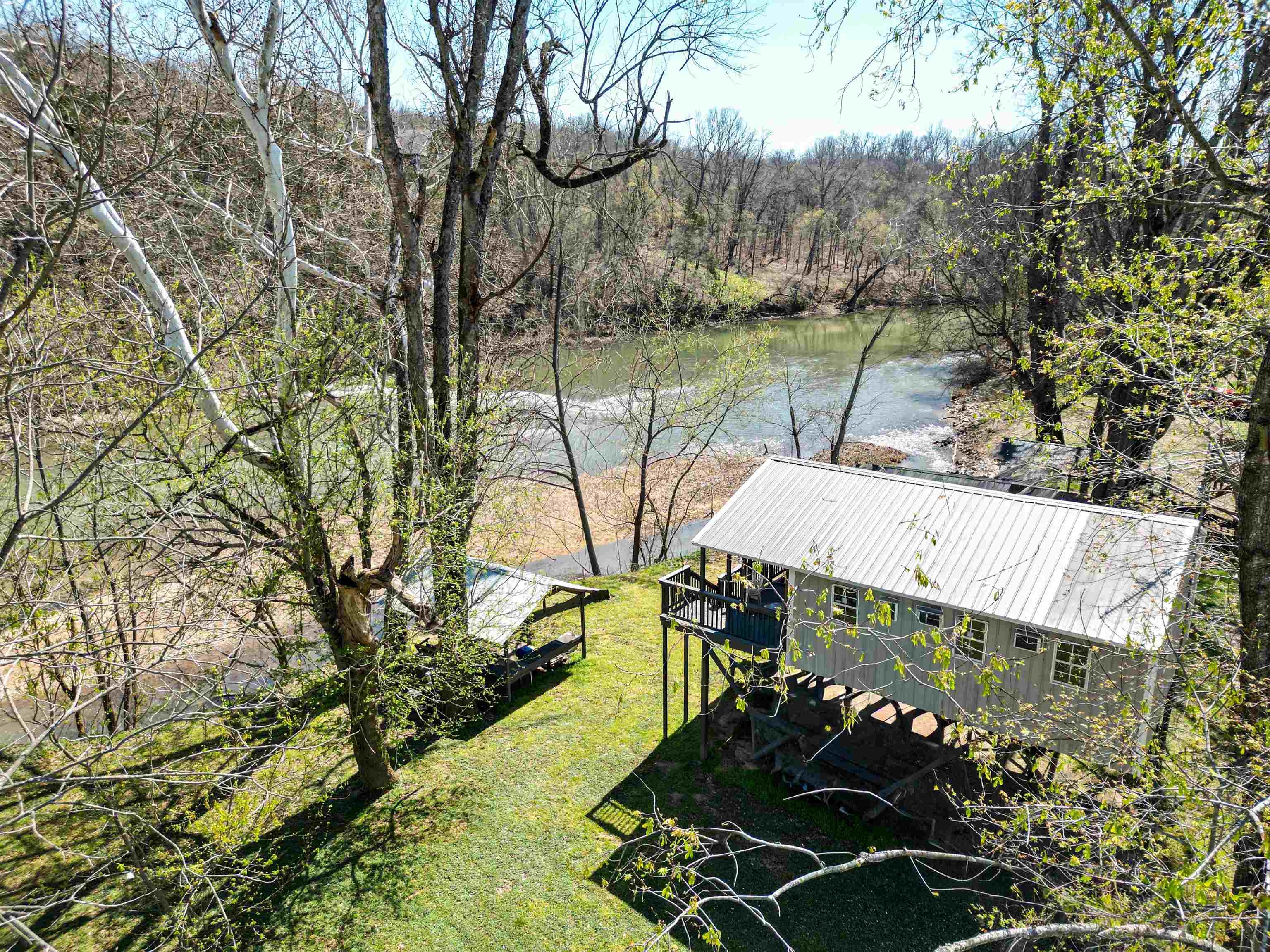Riverfront cabin on the Spring River in Ravenden, Arkansas with easy access to the river and a unique sandbar island perfect for swimming and fishing! This 2-3 bedroom, 2 bath elevated cabin sits on a shaded 100x150 lot with approximately 100 feet of river frontage. The setting offers a rare combination of scenic view of the river plus the relaxing sound of the river rapids near the sandbar.  The metal cabin features a metal roof and has been recently remodeled with fresh interior and exterior paint along with new flooring, making it move-in ready. A covered front porch provides a great place to unwind and take in the peaceful surroundings.  There is a covered pavilion on the bank of the river is ideal for outdoor gatherings, cooking, and enjoying time with family and friends.   If you’ve been looking for a private river getaway with easy access, a usable sandbar, and beautiful Spring River frontage, this is one you don’t want to miss! Located 1/2 mile off the blacktop on a dead end road for seclusion. Just 20 minutes to Hardy, AR known for its many lakes.