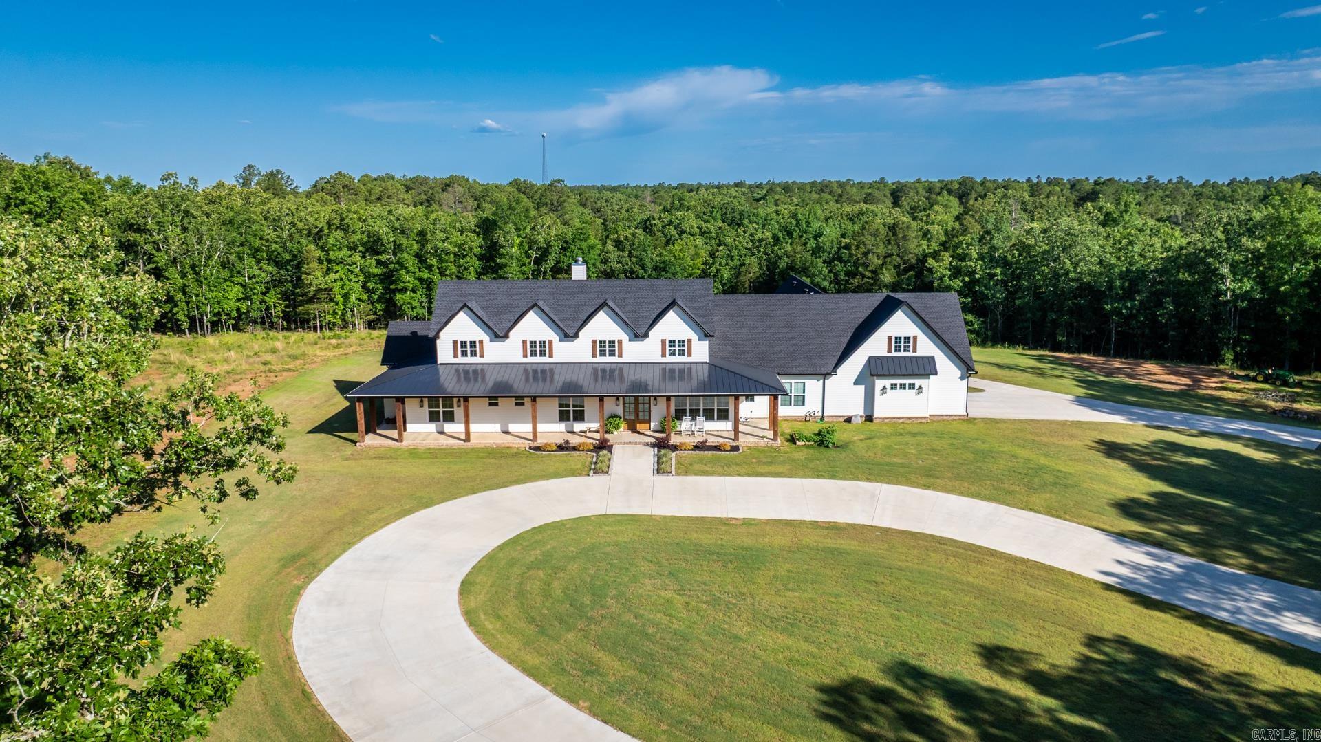 Where Privacy Meets Grandeur- A Rare 40 Acre French County Estate That Redefines Luxury Living. A private drive leads to this stunning French Country Ranch Estate with an unmatched blend of elegance and warmth, across 40 breathtaking acres, complete with a small pond and beautiful wooded views. The wrap-around porch sets the tone for the craftsmanship found throughout, including soaring vaulted ceilings with wood beams, a floor to ceiling stone-accented wood-burning fireplace, rich herringbone brick flooring, and quartzite stone countertops at every turn! The chefs kitchen is a showpiece featuring a professional-grade range, stone backsplash, custom cabinetry, and a fully appointed butlers pantry with wall oven, a second refrigerator, and storage galore. The luxury primary suite is your own private retreat featuring a fireplace, panoramic views of the grounds, dual master closets, and a screened porch of its own with direct access to the resort style gunite pool and spa. The primary bath offers dual toilet rooms, an oversized tile shower, and bespoke finishes. Other Features: 3 bedrooms include their own en suite baths, 2 offices, home gym, safe room, generator & so much more!