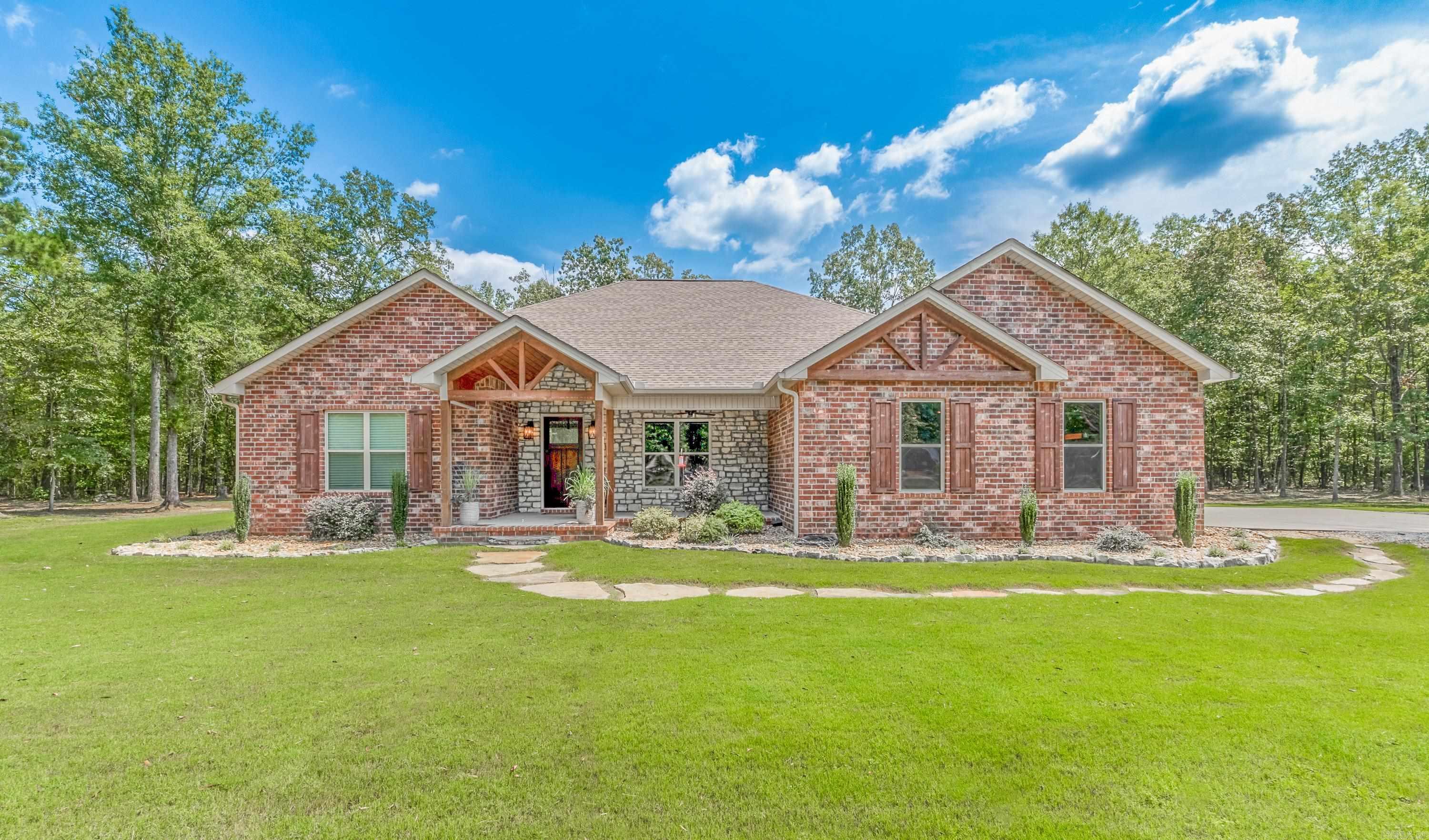 This beautiful 4 bedroom/3 bath home is ready for you to call home. Situated on a lovely wooded 5 acre lot, this stunning property is move-in ready.  As you step inside, you'll be greeted by extra wide doors throughout.  The home features a front great room with exposed beams and a gas log fireplace.  The kitchen area has a beautiful chandalier for over a dining room table.  The spacious kitchen with an extra large island makes for a breakfast bar and is perfect for gatherings. The kitchen offers tons of cabinets, granite countertops, free standing range w/doublee, refrigerator, and vent a hood.  The expansive owner's suite with a large bath that includes a large shower, separate soaking tub, large closets, and double vanities. There are three additional spare bedrooms, one with a private bath, and a Jack & Jill bath.  Wonderful home for any family and 5 wooded acres are exceptional!