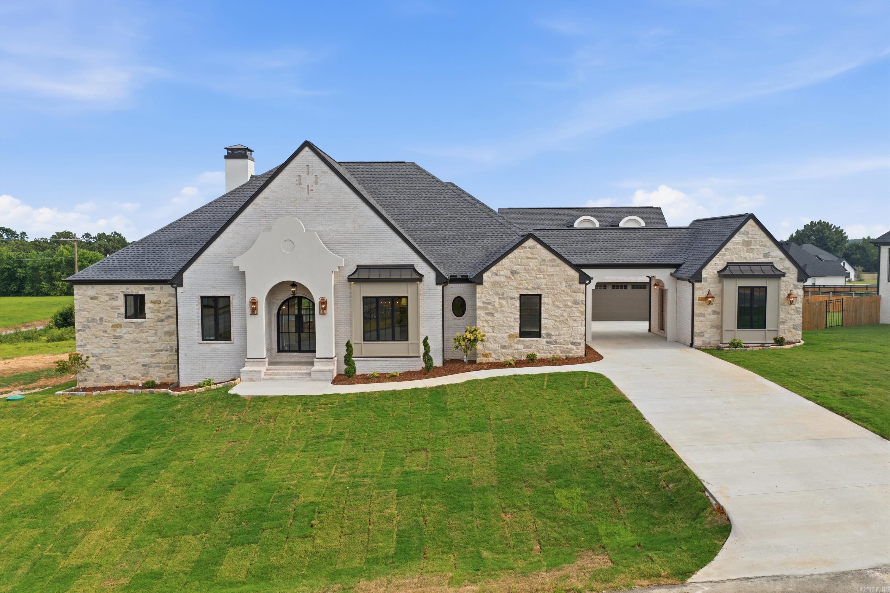 Welcome to luxury living in Highland Hills! Situated on 1.05 acres, this new construction offers a modern French country design with a limestone-wrapped entry, soft arches, custom ceilings, and aged bronze finishes throughout. Featuring 4 BR, 3.5 BA, including a private guest suite, office with built-ins, and bonus room that could serve as 5th BR, this home blends elegance and functionality. The vaulted living room features exposed beams and a gas fireplace, while the gourmet kitchen showcases marble countertops, stainless steel appliances, gas range, pot filler, oversized island, coffee bar with ice maker & wine fridge, and a spacious walk-in Butler's pantry with sink and second dishwasher. The primary suite features a curbless shower, soaker tub, dual vanities, makeup vanity, and oversized walk-in closet. A dramatic porte-cochère adds timeless curb appeal and covered access to the 3-car garage. Additional features include European white oak hardwood and tile flooring, mudroom, laundry room, tankless water heater with recirculating line, and an oversized covered patio with outdoor kitchen and gas fireplace. Agents see remarks.