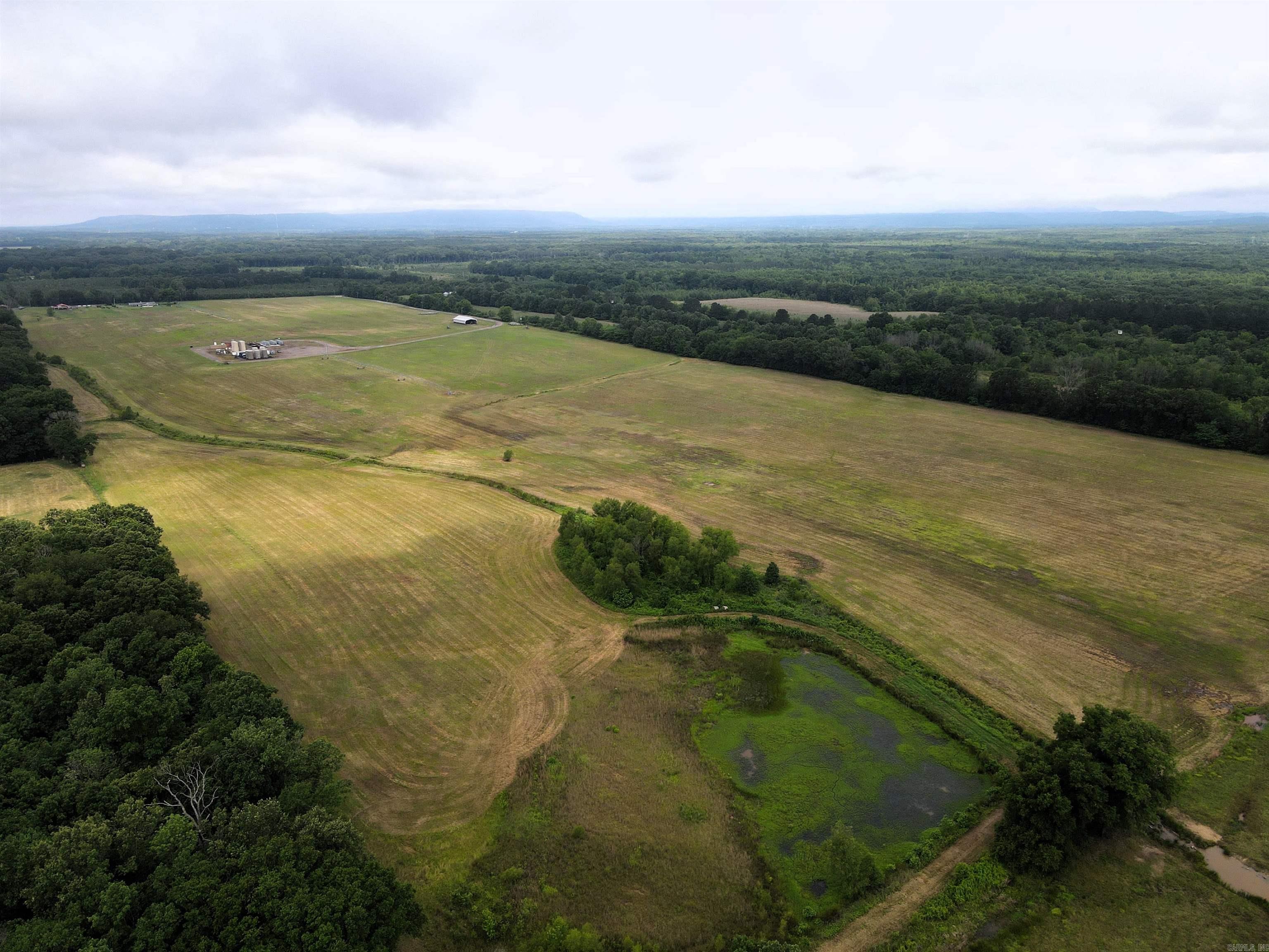 Just outside Morrilton, this 56.82 +/- acre tract offers a hard-to-find combination of usable pasture ground, agricultural improvements, and excellent hunting potential. The land is mostly level and primarily open pasture, making it ideal for livestock, hay production, or creating a rural homestead with room to grow.  A 52 x 80 pole barn provides ample storage for equipment, hay, or farm operations, while the irrigation well adds value for agricultural use. A small creek and pond bring character to the property and help support the healthy wildlife population the area is known for. Partial fencing is already in place, and paved road frontage allows easy access year-round.  For outdoorsmen, the location is tough to beat. The property sits less than half a mile from the Ed Gordon/Point Remove WMA, placing just under 9,000 acres of public hunting and recreation nearby. Conveniently located just 7 miles from both Morrilton and Atkins, this property offers the feel of the countryside without sacrificing access to town.