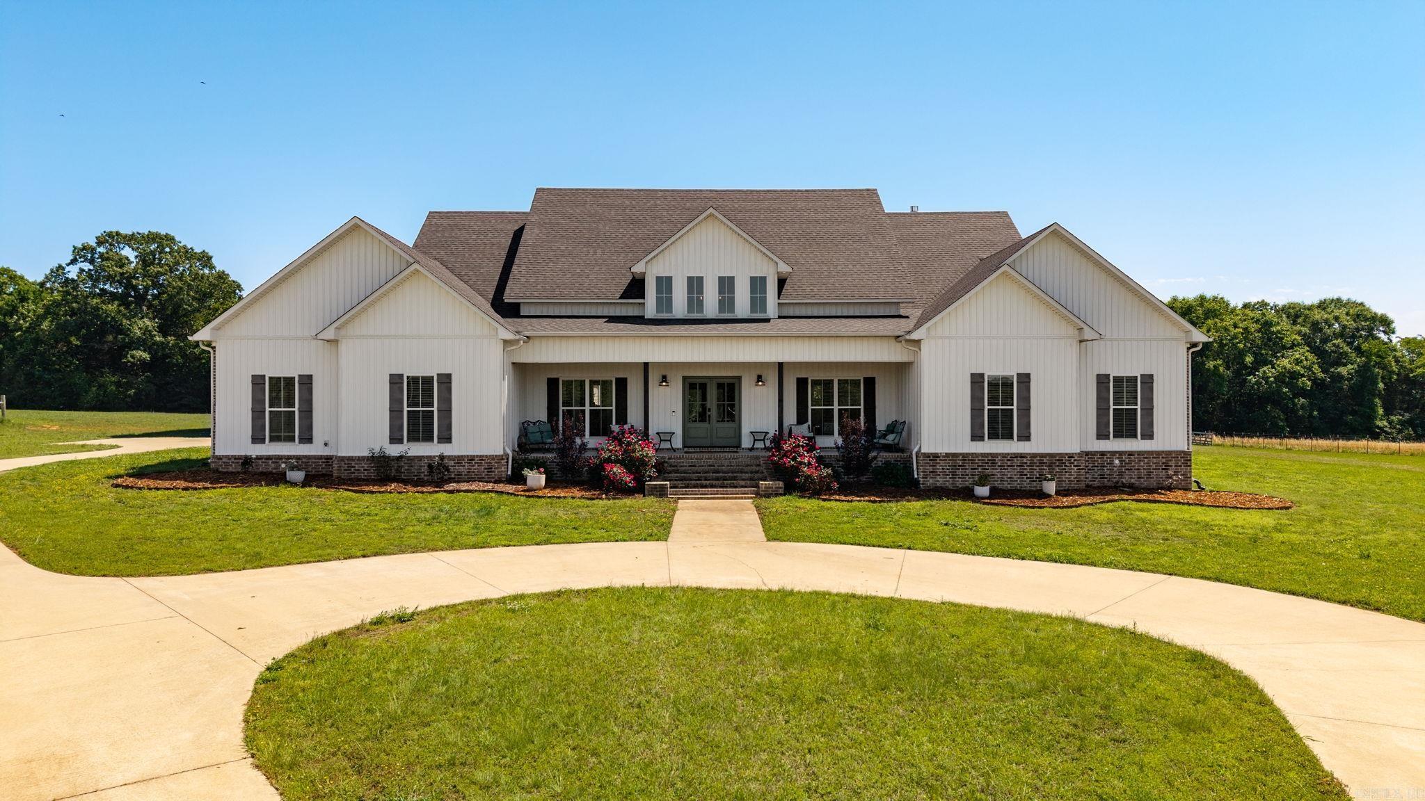 Welcome to this custom home featuring 5 bedrooms, 4.5 baths, 3,536 sq ft built in 2020 on 14.32 contiguous acres in Brookeview Estates. Brick and vinyl exterior. Grand 2-story entry with soaring windows. Custom cabinetry, granite countertops, dual dishwashers, dual ovens, walk-in pantry with dedicated refrigerator, gas fireplace, dedicated office with built-in shelving. Primary suite flows directly to bath, walk-in closet, and laundry. 5th bedroom above 3-car garage with en-suite bath. On-site propane system powers range, gas fireplace, tankless water heater, and whole-home Generac generator. Ground-mounted solar system (financing may convey — ask agent). Buried electric dog fence. Two additional lots (~7 ac) include workshop and storm shelter. Gas pad on property — mineral rights do not convey. Greenbrier School District. 10 min to I-40.