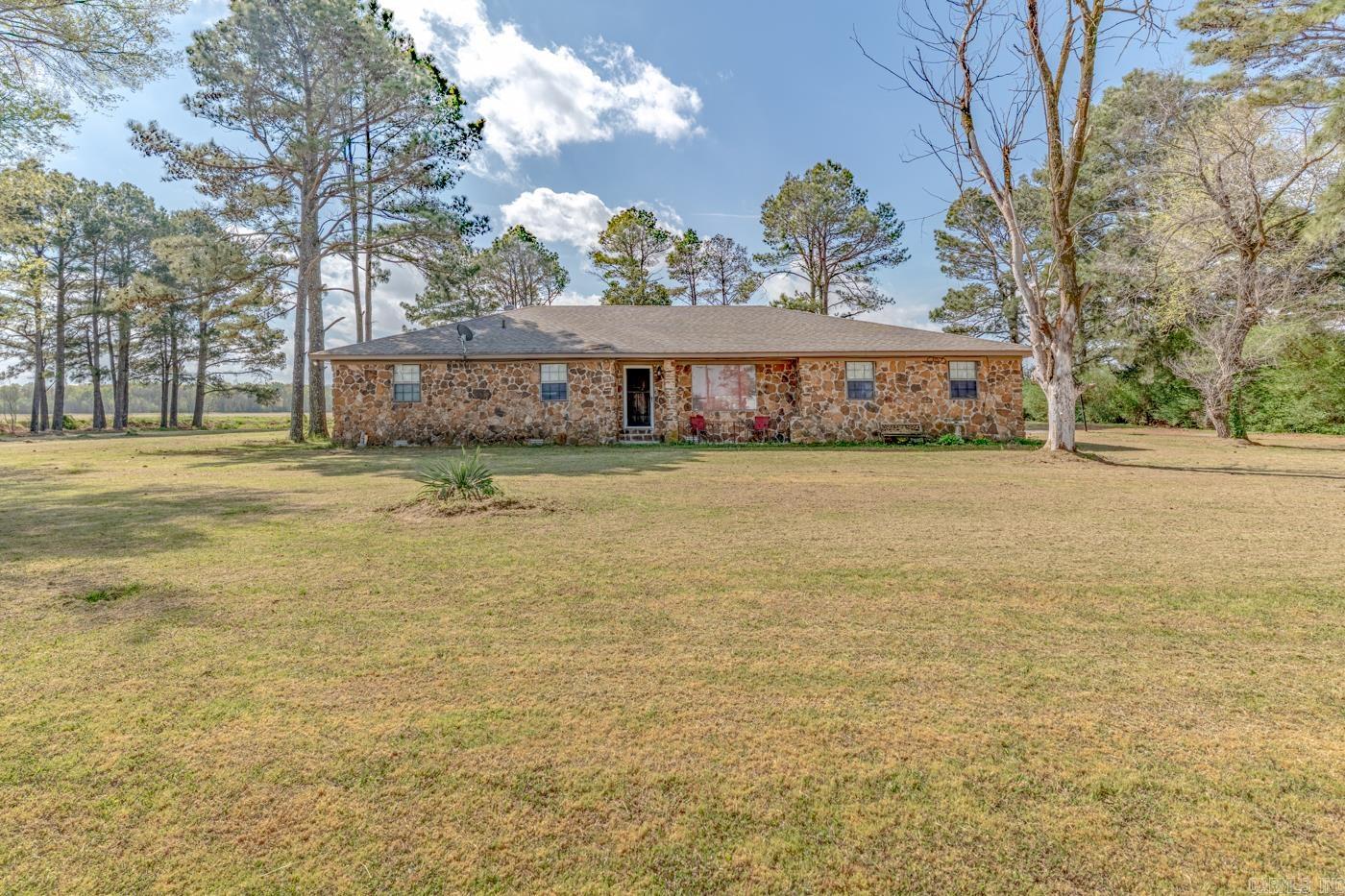 Roof Replaced in May of 2026! Welcome to Market 2115 Highway 64 in Wynne, Arkansas within the Wynne School District. Situated on a .91 +/- acre level lot sprinkled with shade trees, is a 1960 built Ranch style home. The exterior is wrapped in stone, topped with architectural shingles, and accented by a covered front porch, 2 car side entry attached carport, and 440 sf sunroom with wood burning fireplace. The interior features 2,408 sf of well laid out living space and contains a large living room w/ built in shelving and an open concept kitchen/dining area. The kitchen offers bar seating and ample cabinet & countertop space. The Master holds an en-suite with dual vanity and shower/tub combo. The guest wing features a generous bedroom with built-in desk and an en-suite with walk-in shower. 3 additional bedrooms and a large laundry/utility room complete the layout. You'll love the large open yard framed by mature trees and detached outbuilding with metal roof for storage or workspace. Conveniently located just 4 miles to favorite local amenities and less than an hour to Jonesboro, AR and Memphis, TN. Call today to schedule your tour and make this house your home.