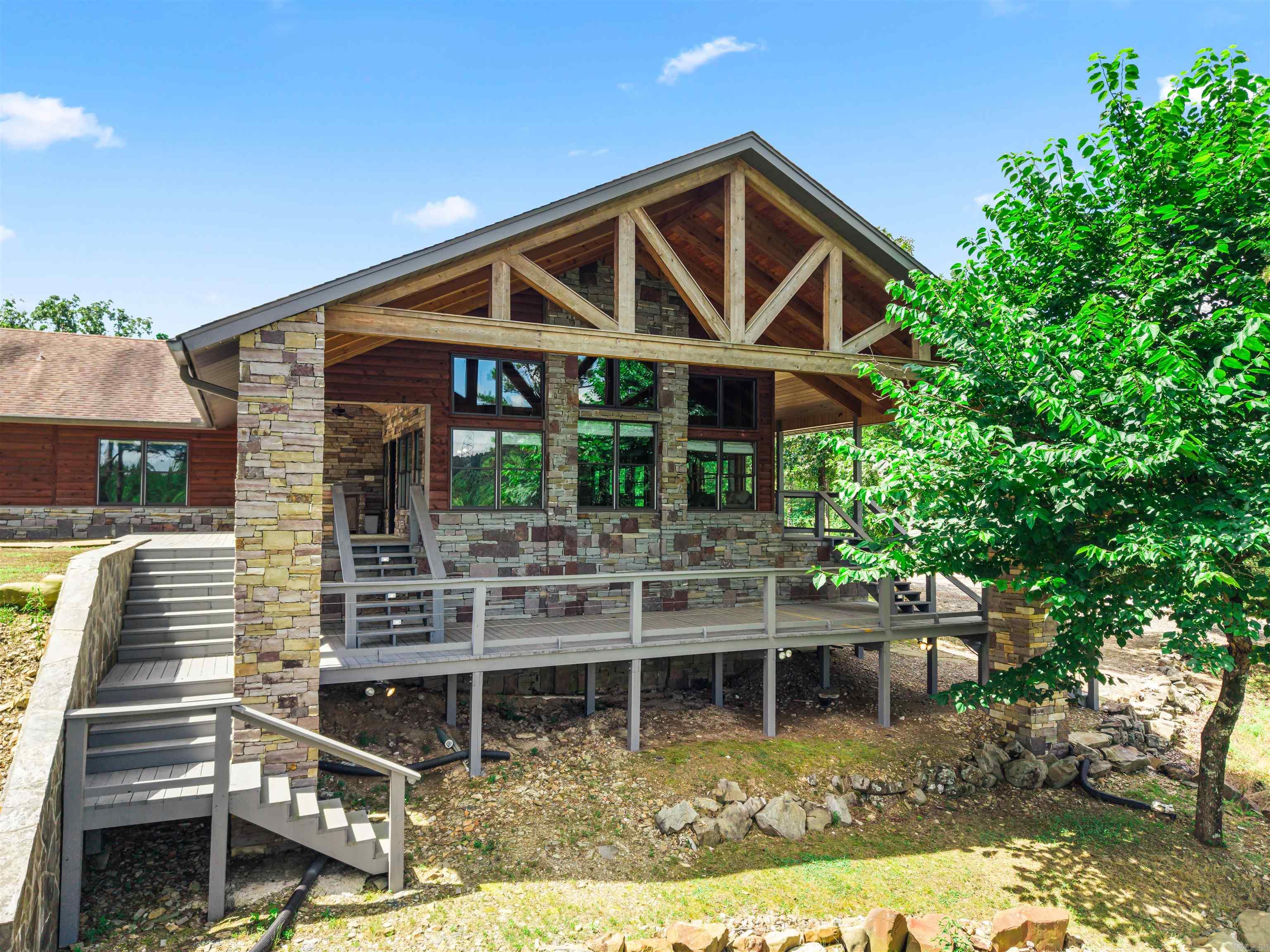 Just minutes from Lake Ouachita, this stunning 12.6-acre compound offers a level of custom craftsmanship rarely seen at any price point.    The main residence features a breathtaking great room addition with soaring cedar cathedral ceilings, massive exposed timber trusses, Pella floor-to-ceiling windows, and a dramatic stacked stone fireplace. The chef's kitchen boasts custom knotty hickory cabinetry, granite countertops, a gas range, and large island. The primary suite includes a spa-style travertine shower, double granite vanity, and cedar-lined walk-in closet.    Outside, a fully equipped outdoor kitchen with Big Green Egg, stone counters, and covered wraparound deck create an entertainer's dream.    A fully functional 2 bed/1 bath second home offers guest, rental, or multigenerational potential. Additional features include a stocked pond, Generac whole-home generator, RV/boat storage building, workshop, and multiple outbuildings — all tucked privately into the Ouachita Mountains. This one is truly in a category of its own.