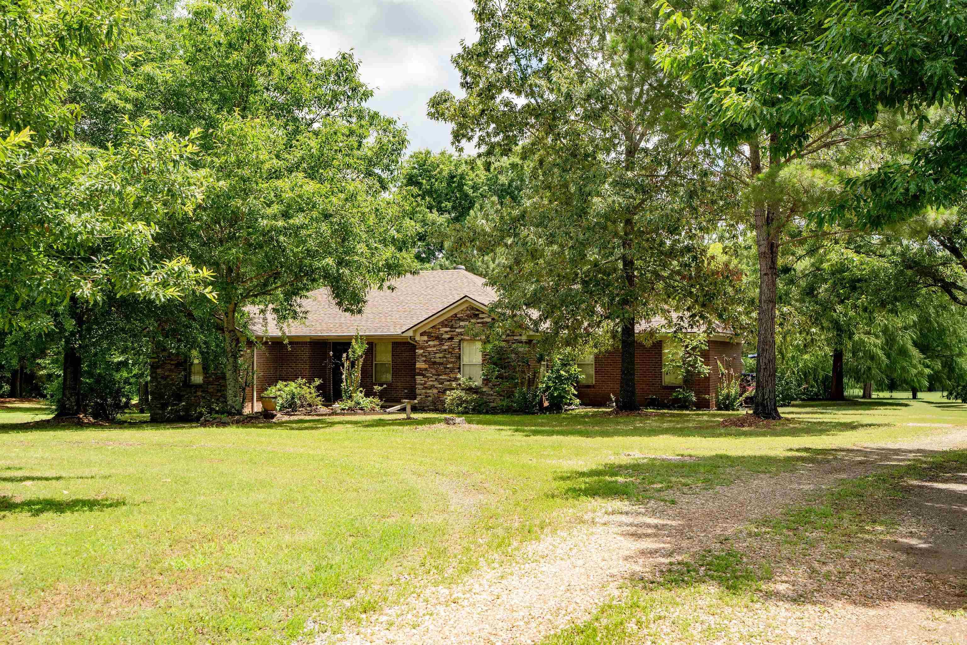 Country Luxury on 25.27 Acres | Pond, Shop, Boat Garage & Hunting Land  Beautiful 3BR, 2BA brick and stone home on 25.27 acres in the Quitman School District. Built in 2005, this 2,291 SF home features hardwood and tile floors, crown molding, built-in bookcases, and a spacious living room with wood-burning stove. Enjoy year-round views from the 300 SF sunroom with fireplace or the 300 SF deck overlooking the property.  The kitchen offers solid wood cabinetry, rollout pantry drawers, double ovens, dishwasher, breakfast area, and dual-ice maker refrigerator. The private primary suite includes a walk-in closet with safe, double vanity, jetted tub, and separate shower.  Property features include a 3-car garage with underground storm shelter, new roof (2022), new heat pump (2023), Generac 28KW whole-house generator, and large laundry room. Approximately 10 acres are mostly cleared and ideal for deer and turkey hunting, with remaining wooded acreage and a pond.  Additional amenities include a 42'x45' boat garage, 24'x38' spray-foam insulated shop with separate electric meter, 50-amp RV hookup, and zero-turn mower included. Privacy, recreation, and country living at its best!