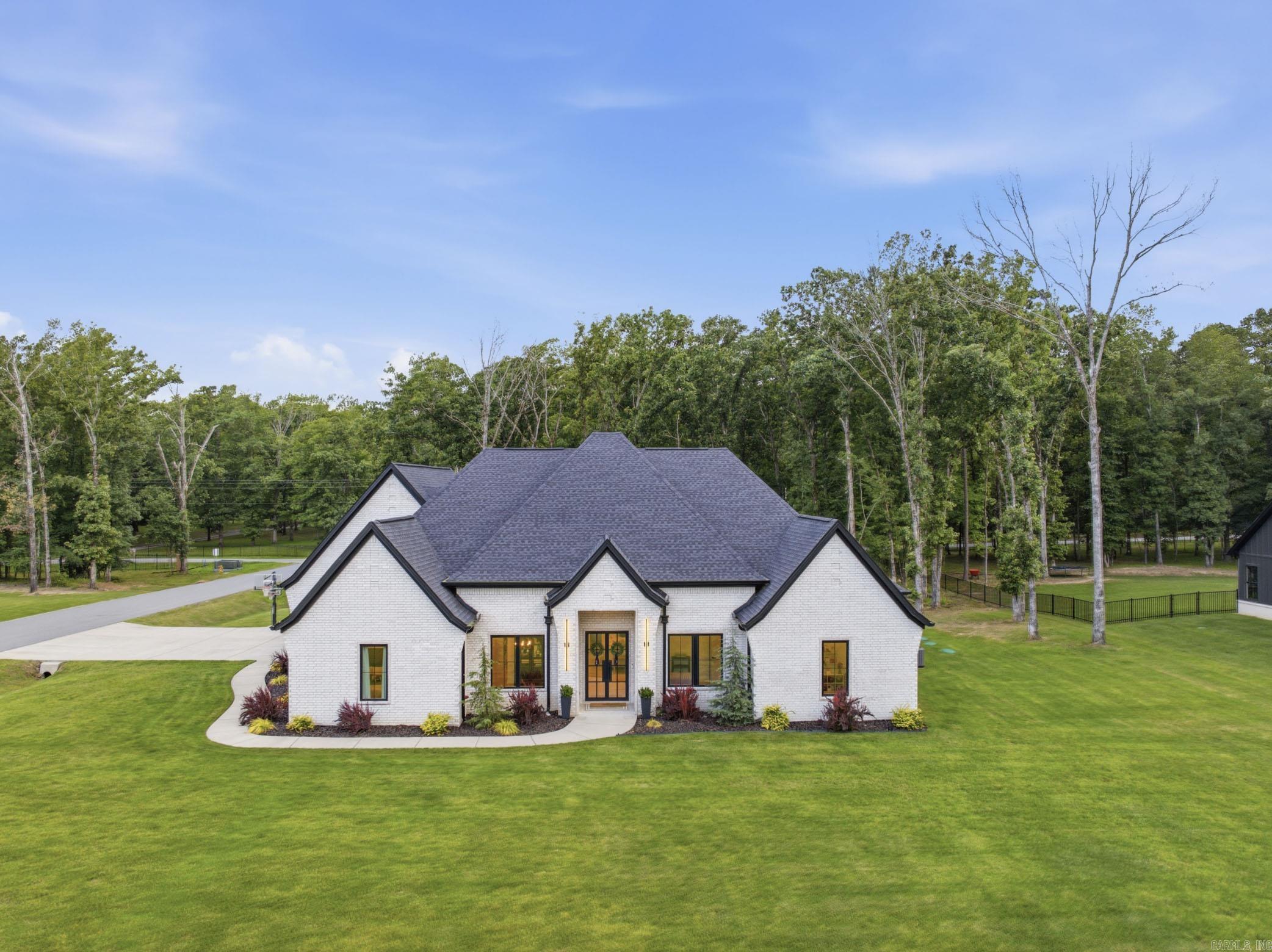 Tucked away on just over an acre and framed by a backdrop of mature trees, this custom-built home offers the perfect balance of luxury, privacy, and everyday convenience.  With over 3,700 square feet, 4 bedrooms, and 3 baths, the thoughtfully designed floor plan centers around a stunning open-concept living space where soaring ceilings, oversized windows, and warm natural finishes create an inviting atmosphere. The kitchen is both beautiful and functional, featuring an oversized island, custom cabinetry, a walk-in pantry, double ovens, a gas range, and a full suite of matching Café appliances.  The primary suite serves as a true retreat with its own fireplace and a spa-inspired bath complete with a freestanding soaking tub, dual walk-through showers, and a thoughtfully designed layout.  Outside, the covered outdoor living area was built for year-round enjoyment, featuring a fireplace, TV, outdoor kitchen, and plenty of space to gather with family and friends while enjoying the wooded surroundings.  Located in Alexander with easy access to Benton, Bryant, and Little Rock, this home offers the perfect balance of convenience and privacy.
