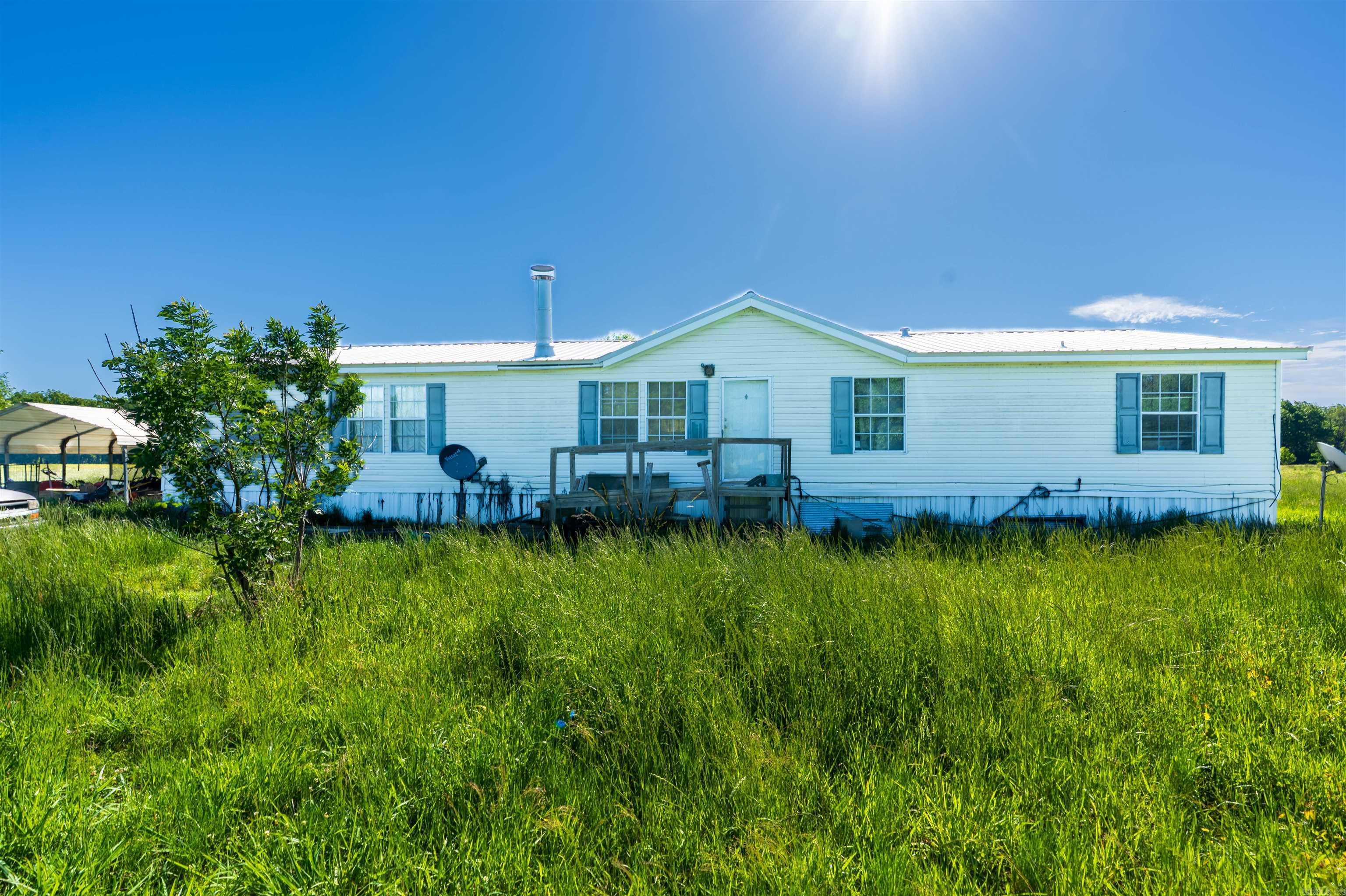 Discover the potential of this country property situated on over an acre of open land, offering privacy, space, and endless opportunities. This manufactured home features a spacious layout with multiple living areas, a large kitchen, and generous bedroom sizes. The property includes an additional covered structure and plenty of outdoor space for storage, gardening, recreational use, or future improvements.  The home will require repairs and updates throughout, making it an ideal investment opportunity or project for buyers looking to customize a property to their needs. With its wide-open surroundings and rural setting, this property offers a peaceful lifestyle with room to grow.  Whether you're seeking acreage, value, or a renovation project, this property provides the foundation to create something truly your own.