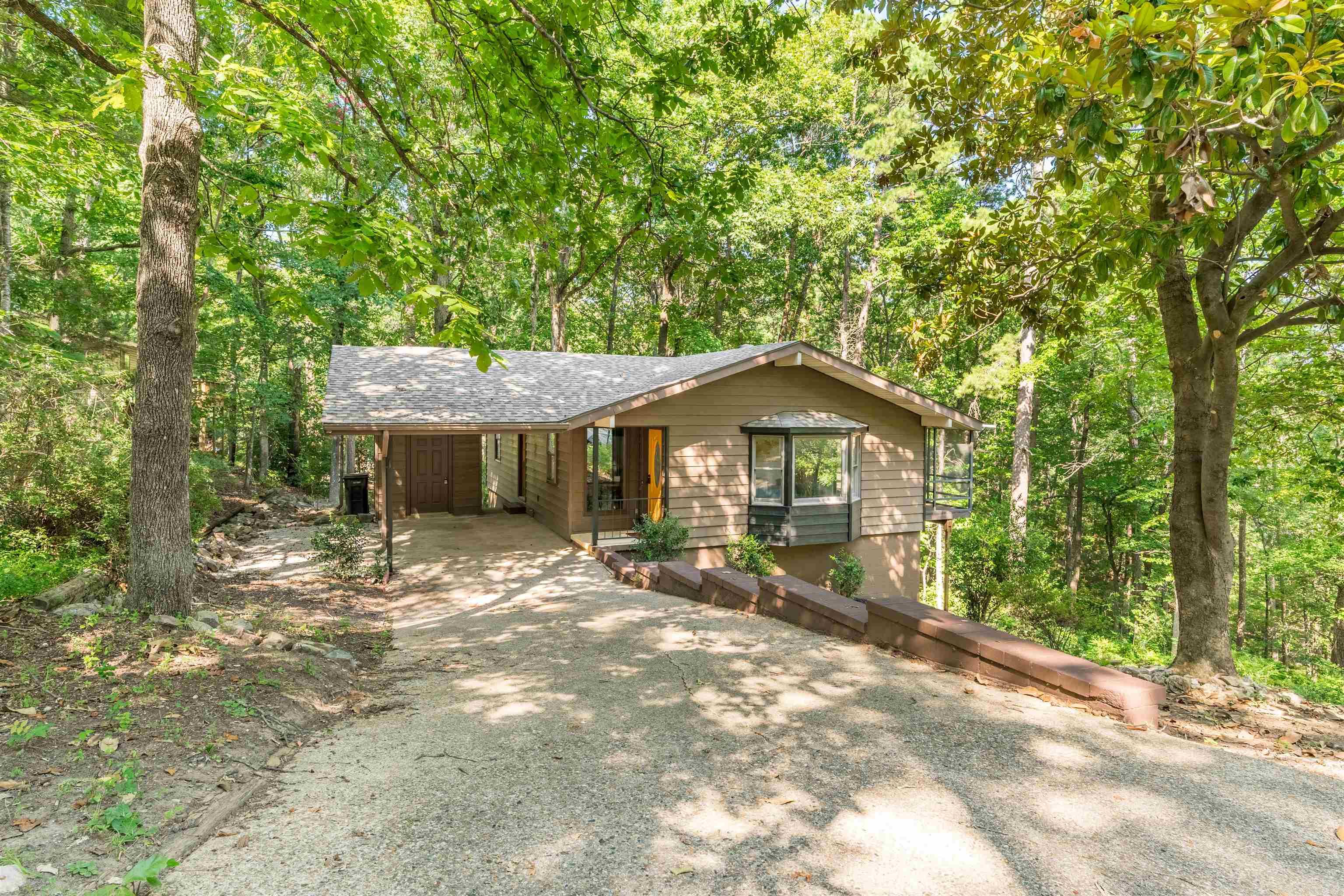 PRICE IMPROVEMENT!! Welcome to your private treetop sanctuary in Hot Springs Village! This completely remodeled 3-bed, 2-bath, 2,062 sq ft home delivers an incredible "treehouse vibe" at the end of a quiet cul-de-sac near the West Gate. The main level boasts gorgeous luxury vinyl plank (LVP) flooring, a new roof, and a stunning kitchen with warm butcher block countertops and soft-close cabinets. The highly versatile, fully finished lower level features a built-in bar, a safe room, and a 2nd washer/dryer hookup—perfect for a second living space, a hang-out, or a private master suite. Step outside to immerse yourself in nature from the screened porch or the oversized upper and lower decks. An oversized carport with attached storage provides ample room for vehicles and golf carts. Enjoy the Village’s world-class amenities: championship golf, pristine lakes, miles of trails, and fitness centers. This unique property perfectly blends modern luxury with a peaceful, natural escape!