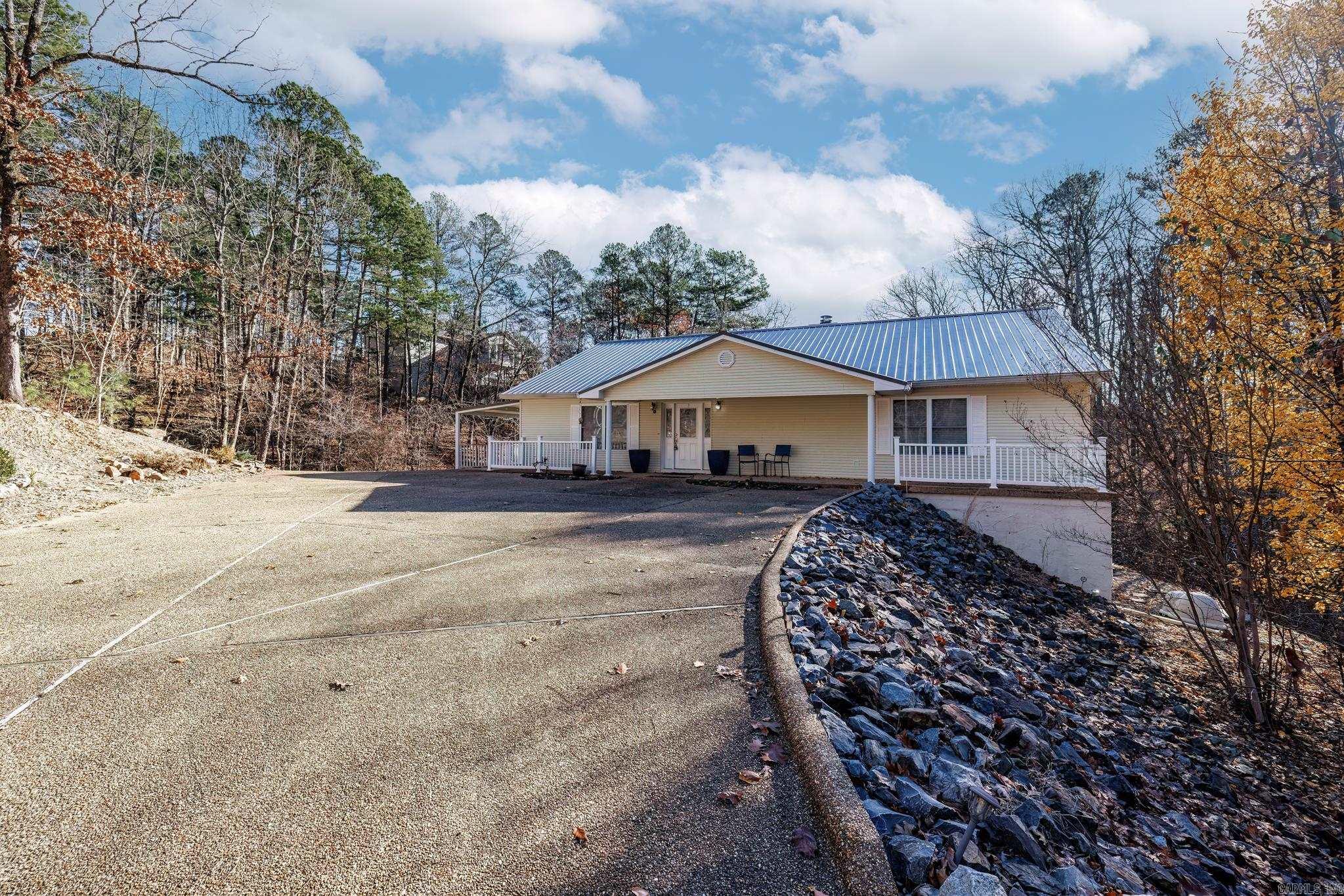 Centrally located in Hot Springs Village you will find this gem on Lake Coronado with a spacious lot.  This is a steel construction home with great views on your private oasis. Kitchen with granite counters open to the living/dining area. Upper level has primary bedroom and bath and an additional guest bedroom and bath. Lower level with living area, guest bedroom and full bath. Drive around back of the home to oversized garage for plenty of car and toy storage!  Easy walk to the lake and boat dock. Metal roof 2023. Carpet 2023.  See Agent Remarks.