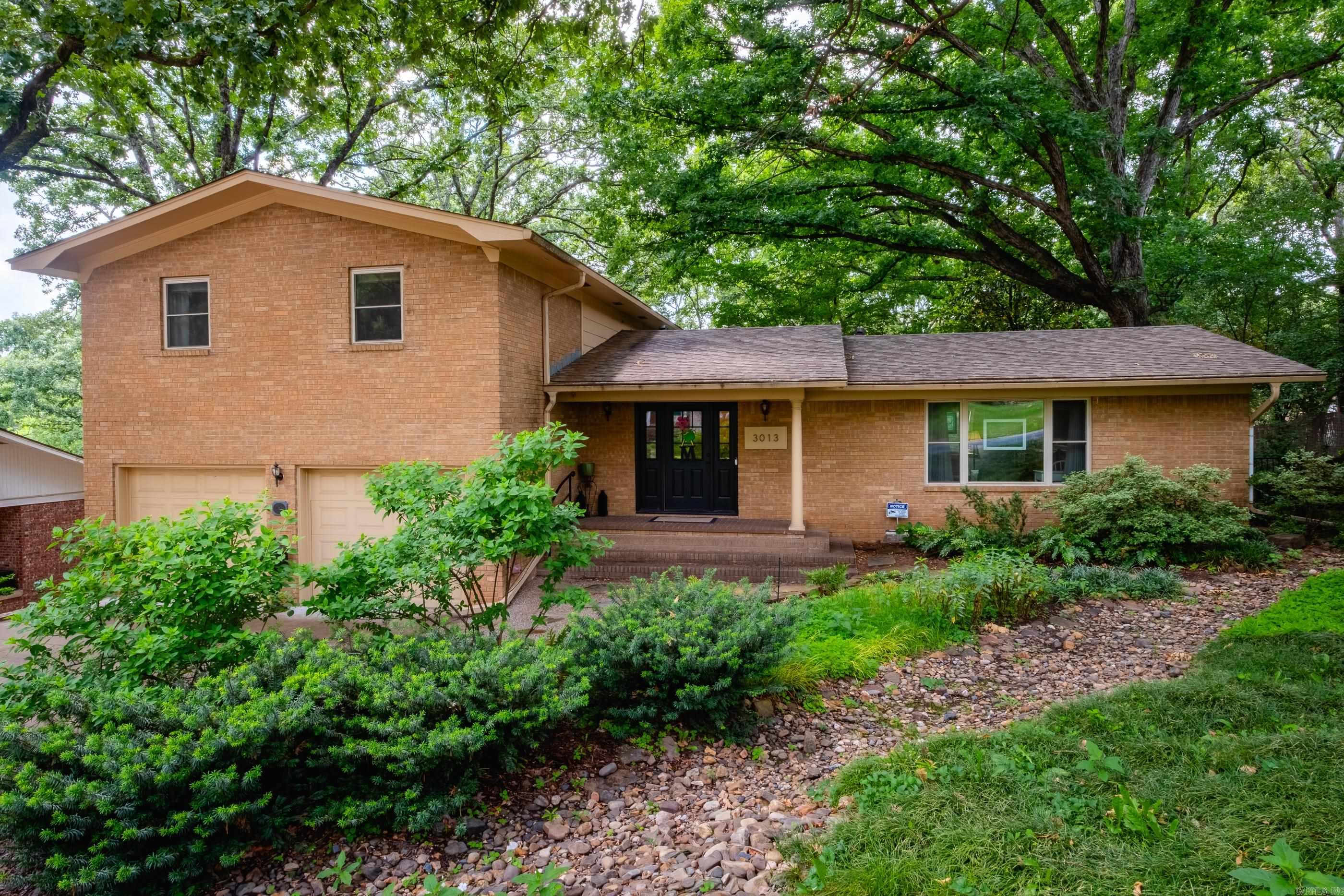 Nestled within the Lakewood neighborhood in North Little Rock, this home offers the perfect blend of convenience, character, and outdoor charm. Enjoy being just minutes — or even a short walk — from shopping, restaurants, parks, and the neighborhood lakes.  The backyard is truly a private oasis and a gardener’s dream, featuring lush outdoor spaces and three separate decks, including one directly off the primary bedroom.  Inside, you’ll find two comfortable living areas. One living space features a wet/coffee bar, making it ideal for entertaining or cozy nights at home. The kitchen features a cheerful bay-window dining area filled with natural light. 3/4 inch hardwood floors throughout - zero carpet! The roof was replaced in 2025.  All three bedrooms are located upstairs (with a laundry shoot to the laundry room), creating a functional layout with privacy from the main living spaces. In addition to the main 2-car garage, there is a heated and cooled workshop/storage area with an additional garage space, perfect for hobbies, tools, recreational vehicles, or larger “toys.” 6" reinforced concrete walls in the workshop make for a perfect storm shelter. Vast storage spaces.