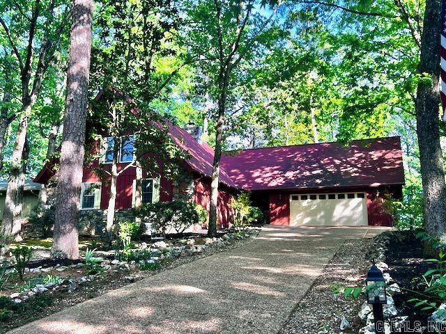 Tucked among trees in beautiful Hot Springs Village, this contemporary retreat blends architectural drama with warm, inviting living spaces. Step inside to a breathtaking great room where soaring vaulted ceilings & a wall of windows flood the space with natural light, framing serene wooded views. Newly installed engineered hardwood floors, modern ceiling fans, and a stone fireplace anchor the room—perfect for both relaxing evenings & entertaining guests. The updated kitchen is a standout feature, offering sleek white cabinetry, stainless appliances, & expansive butcher block countertops. A unique stone accent wall adds character, while the galley layout provides stylish function. The home features spacious bedrooms with fresh, neutral finishes & plush carpeting - a comfortable retreat for family & guests. Updated bathrooms showcase contemporary design, elegant lighting & a clean, modern aesthetic. Outdoor living is just as impressive. An expansive deck invites you to unwind, entertain, or simply enjoy the peaceful surroundings. With its distinctive architecture, thoughtful updates, & tranquil setting, this home offers the perfect blend of style, comfort, & nature.